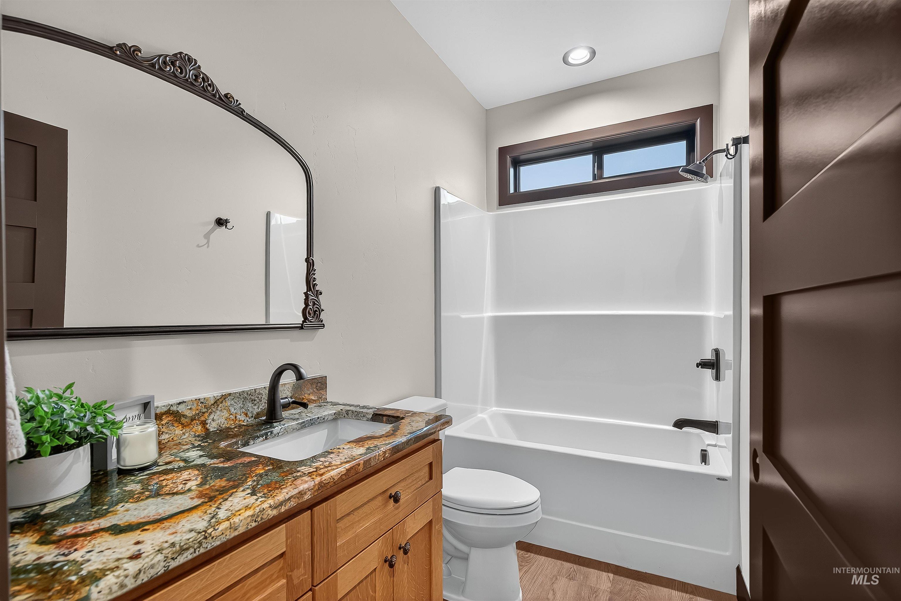 Bathroom featuring vanity,  shower combination, and light wood-style flooring