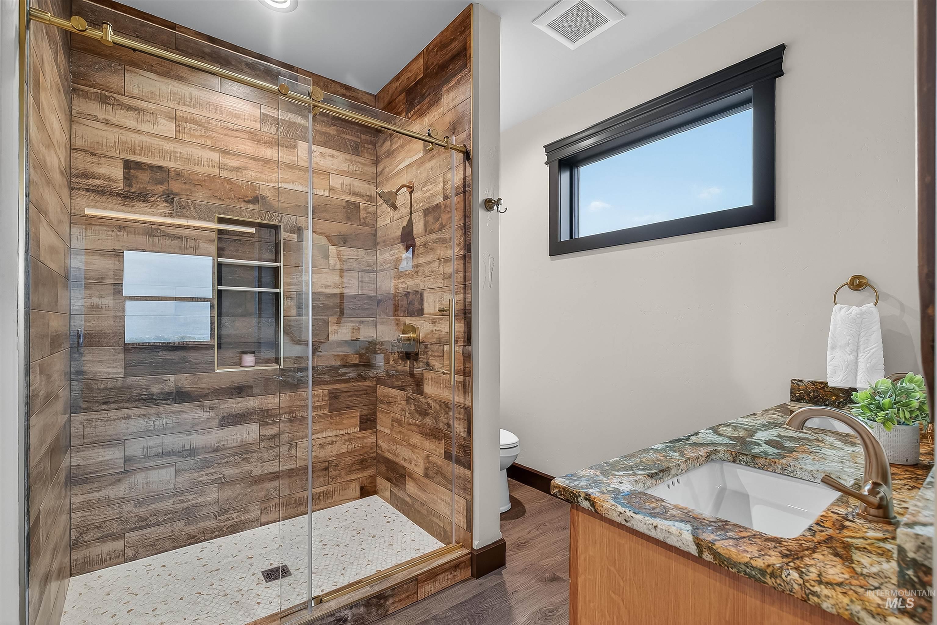 Bathroom featuring double vanity, a shower stall, and dark wood finished floors