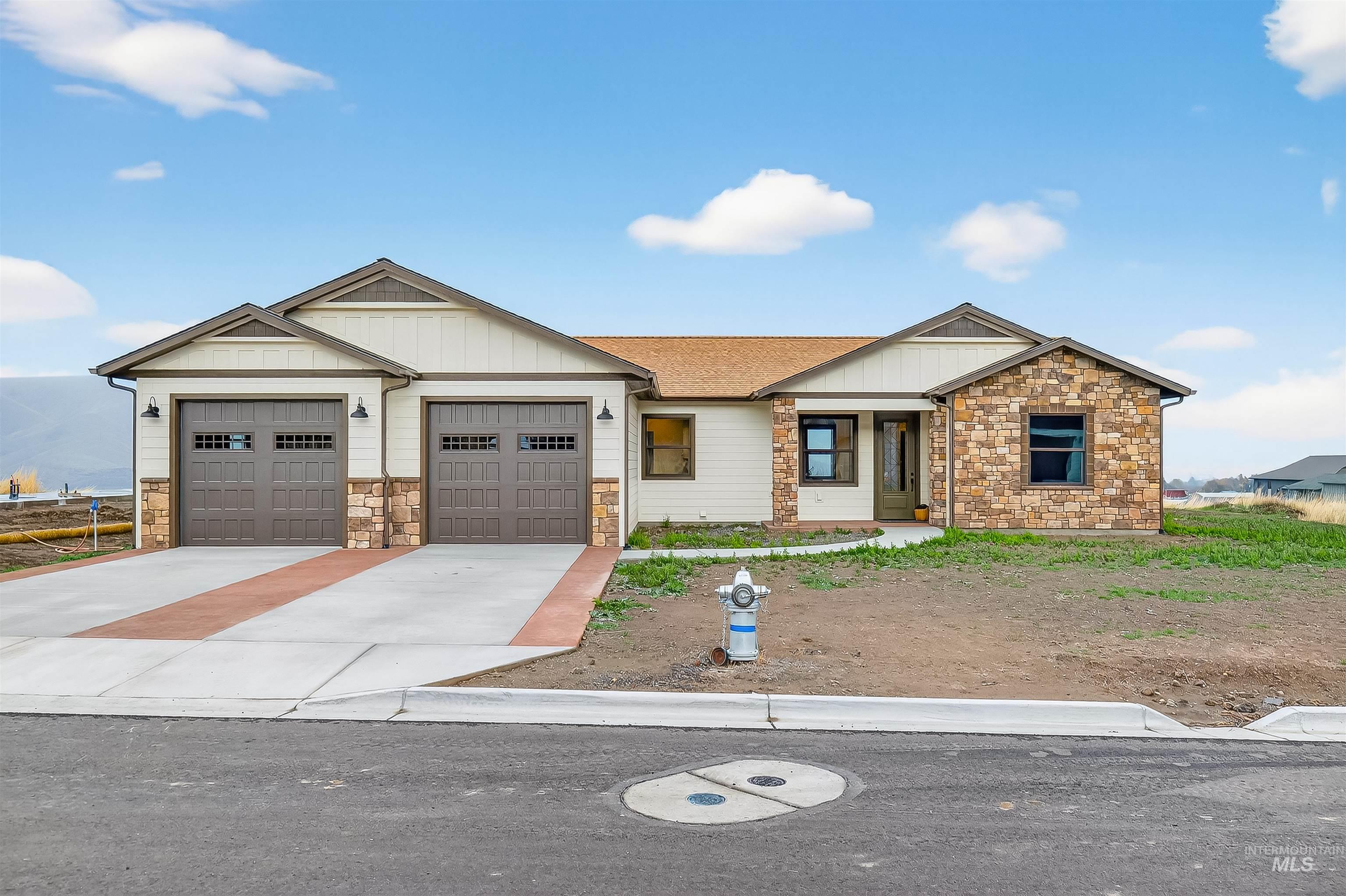 View of front of home with board and batten siding, concrete driveway, stone siding, a garage, and roof with shingles