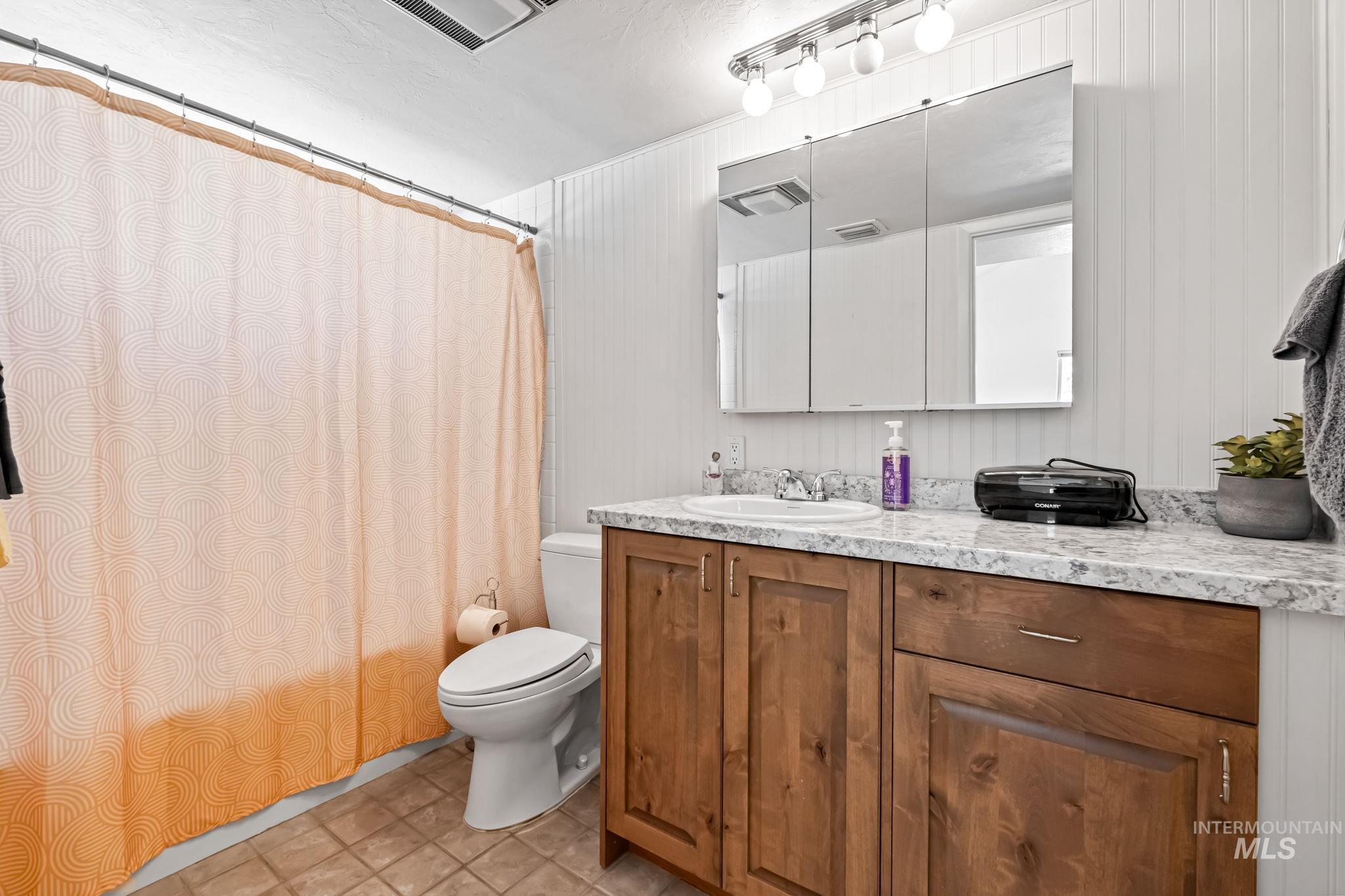 Bathroom featuring vanity, shower / bath combo with shower curtain, and tile patterned flooring