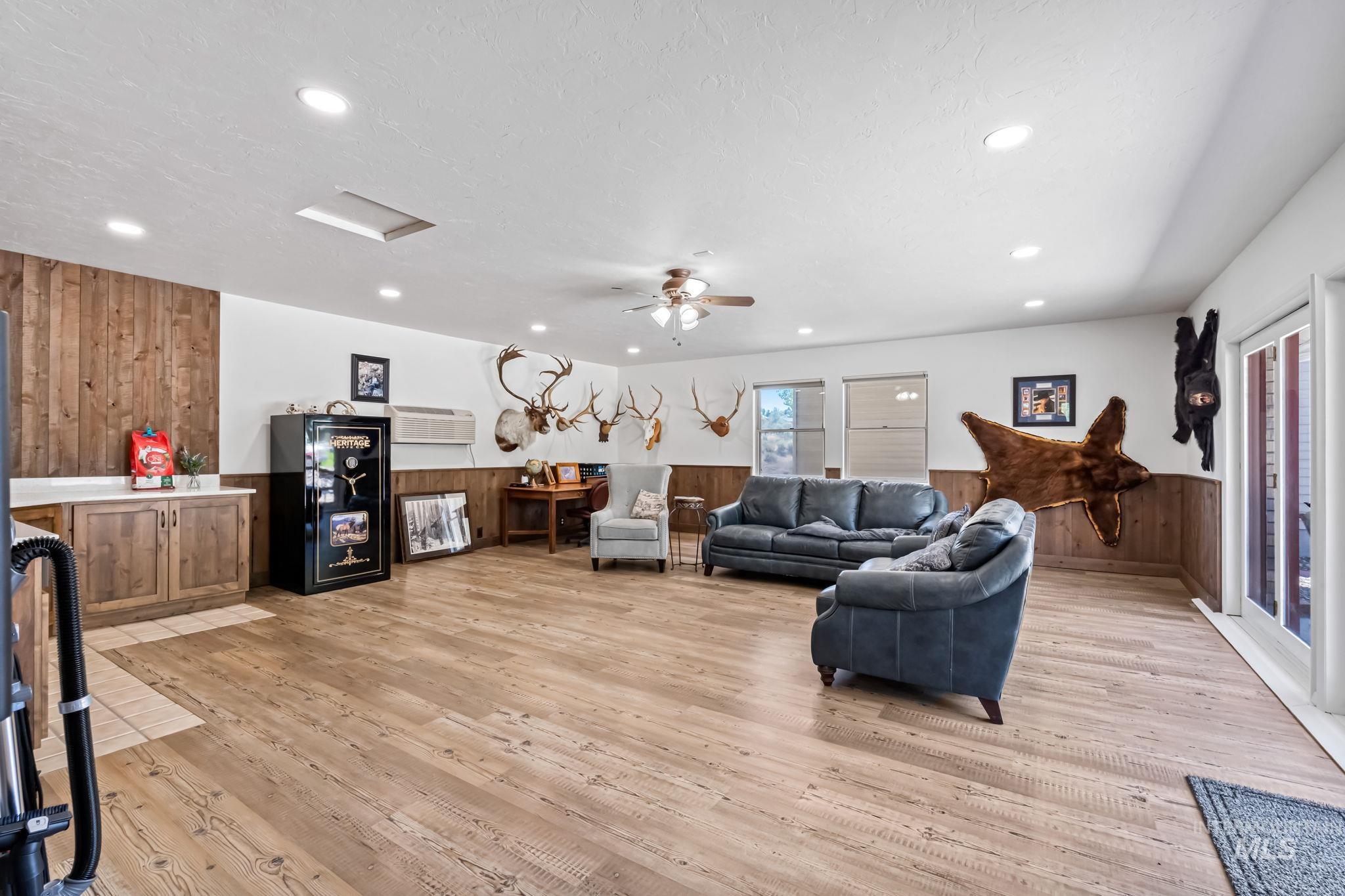 Living area featuring attic access, light wood-style floors, recessed lighting, a wainscoted wall, and a ceiling fan