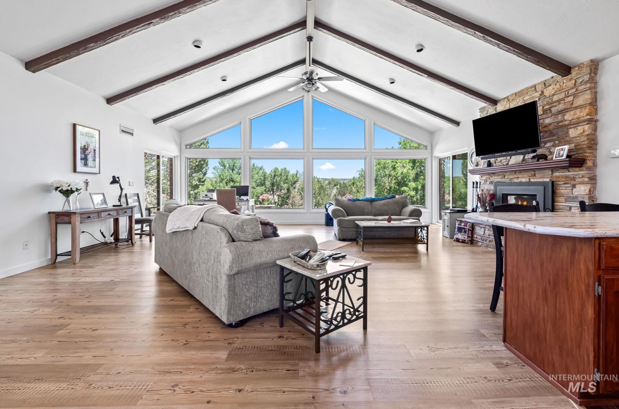 Living room featuring plenty of natural light, beamed ceiling, a fireplace, light wood-type flooring, and high vaulted ceiling
