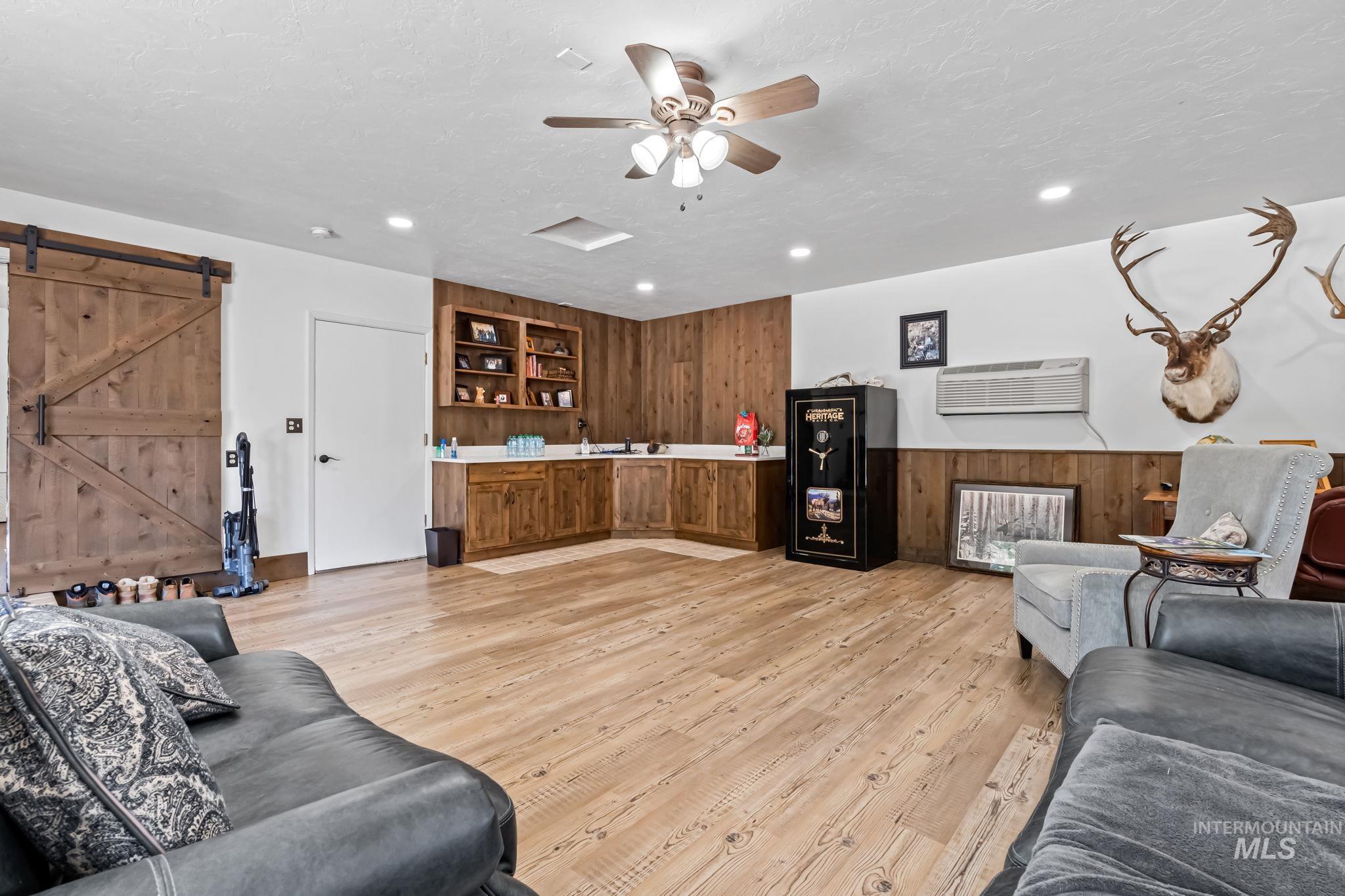 Living area featuring a barn door, a wall mounted AC, recessed lighting, light wood finished floors, and wood walls