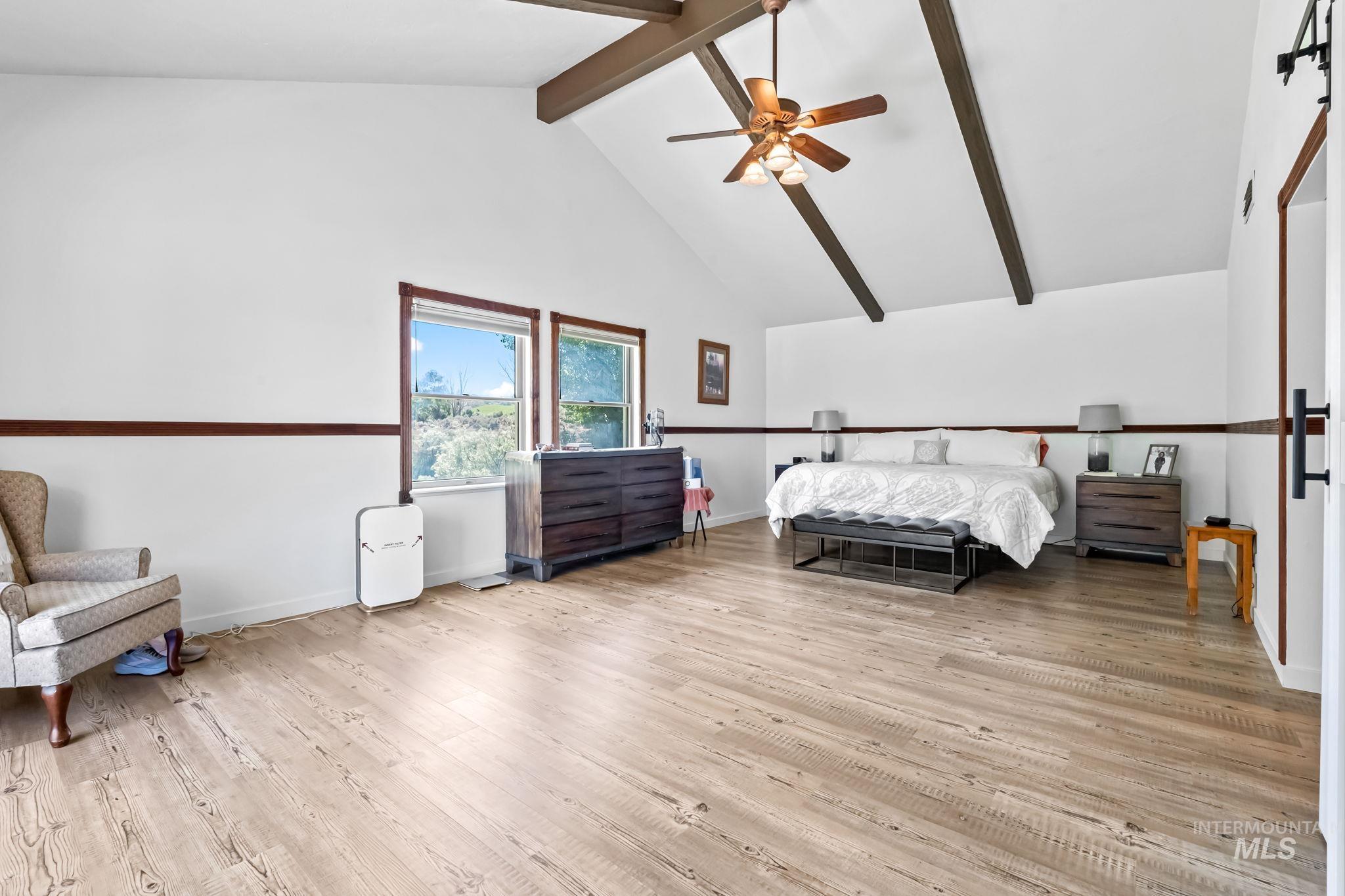 Bedroom featuring beam ceiling, wood finished floors, high vaulted ceiling, and ceiling fan