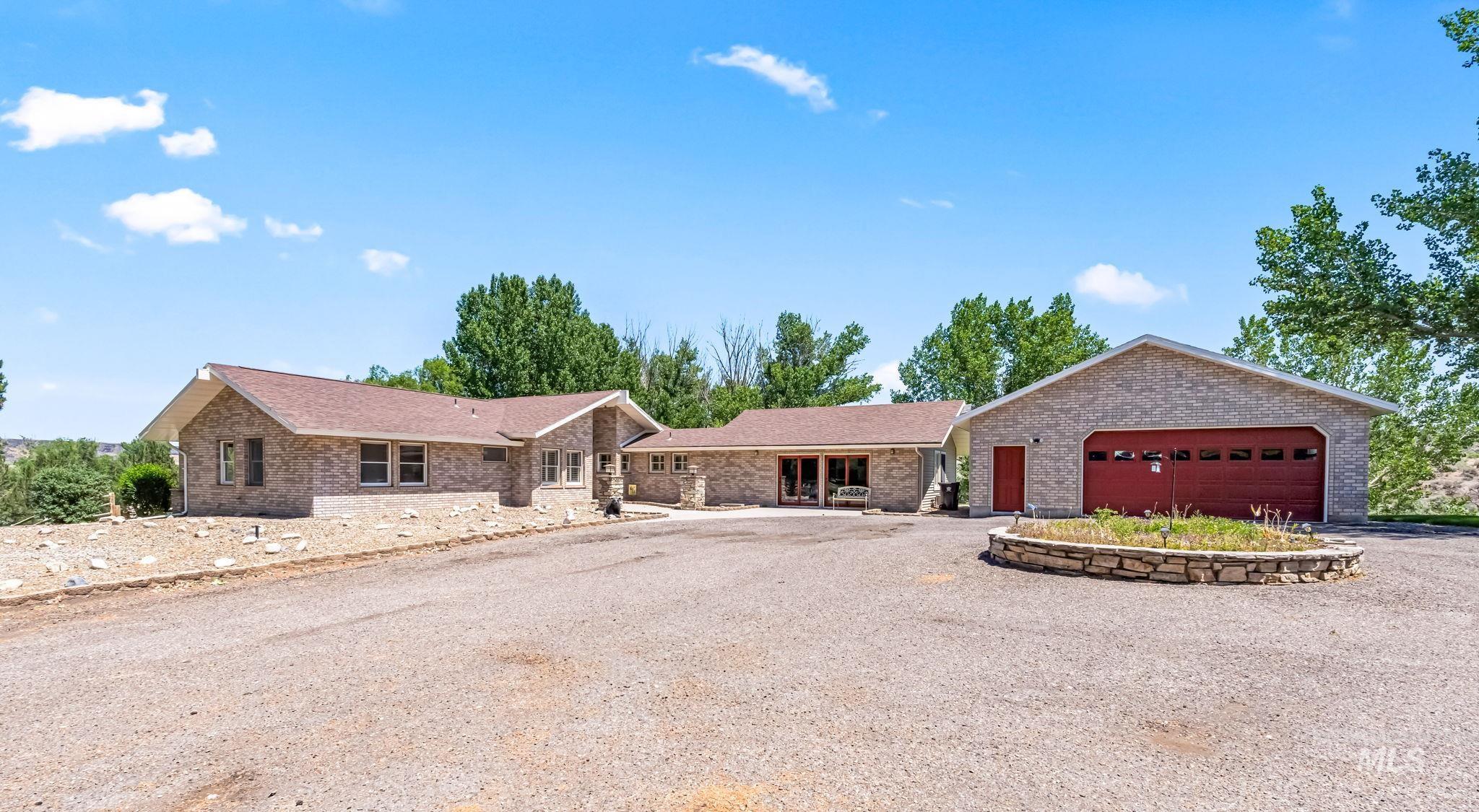 Single story home with gravel driveway, brick siding, and an attached garage