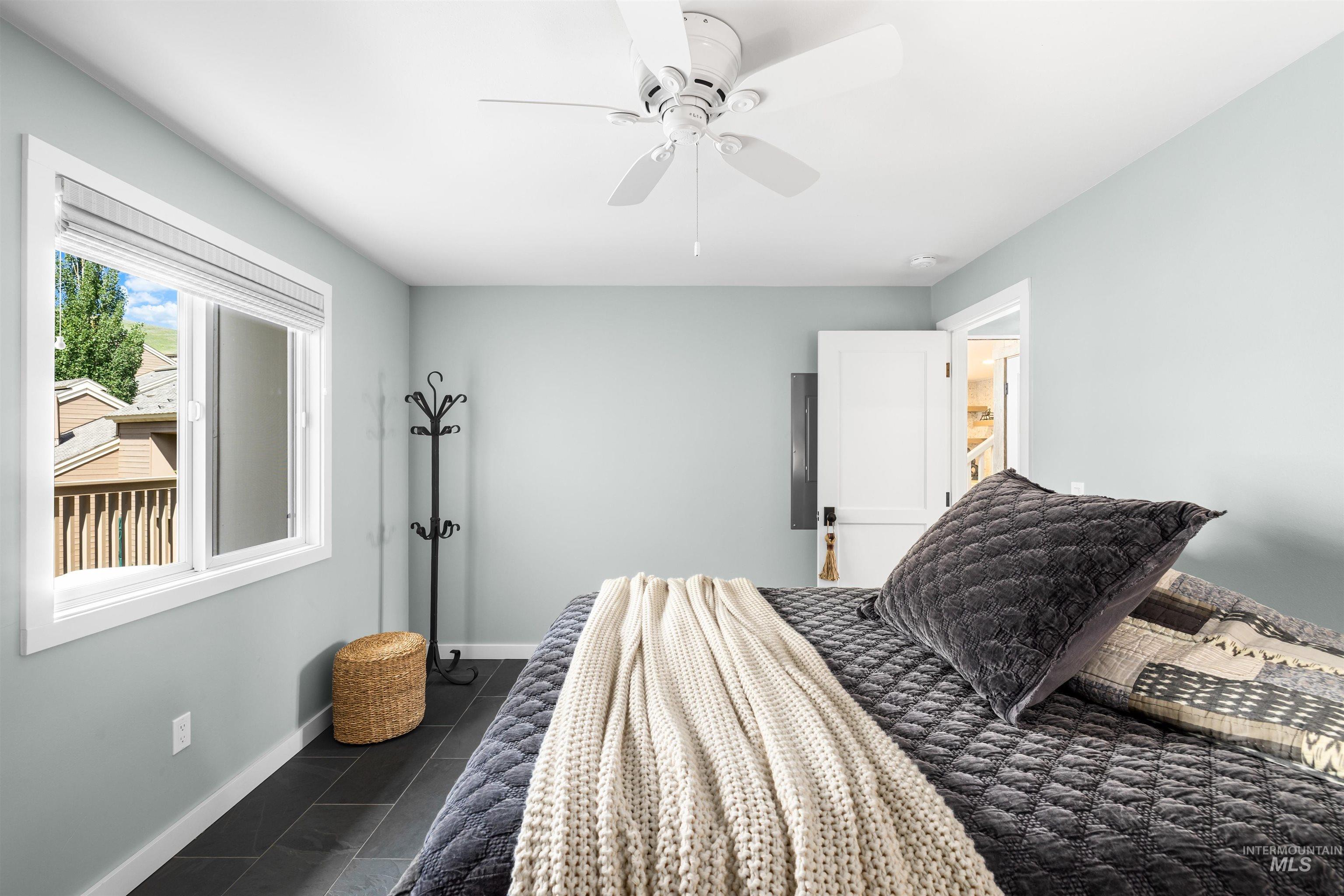 Bedroom with dark tile patterned flooring and ceiling fan