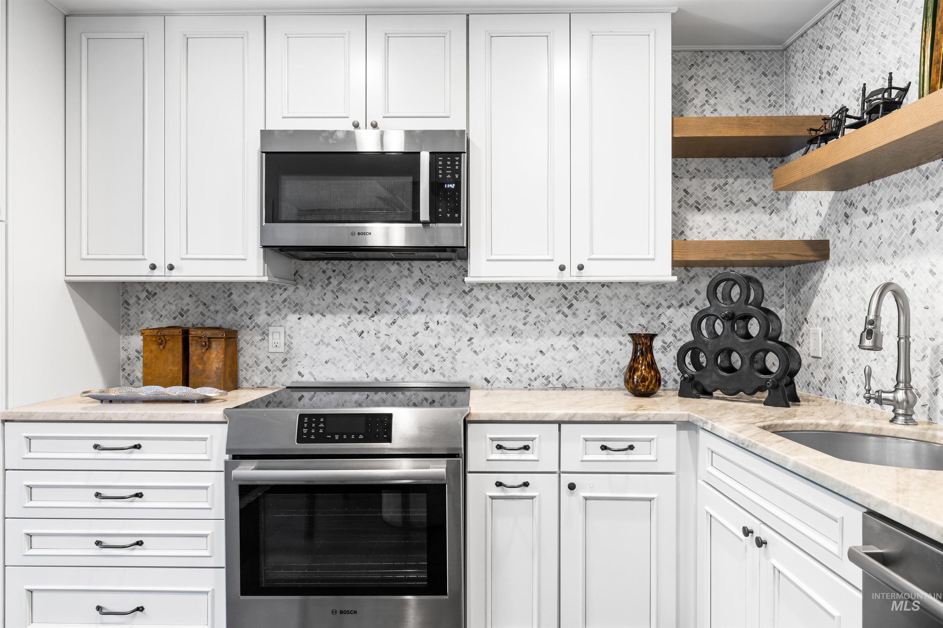 Kitchen with appliances with stainless steel finishes, open shelves, backsplash, and white cabinets