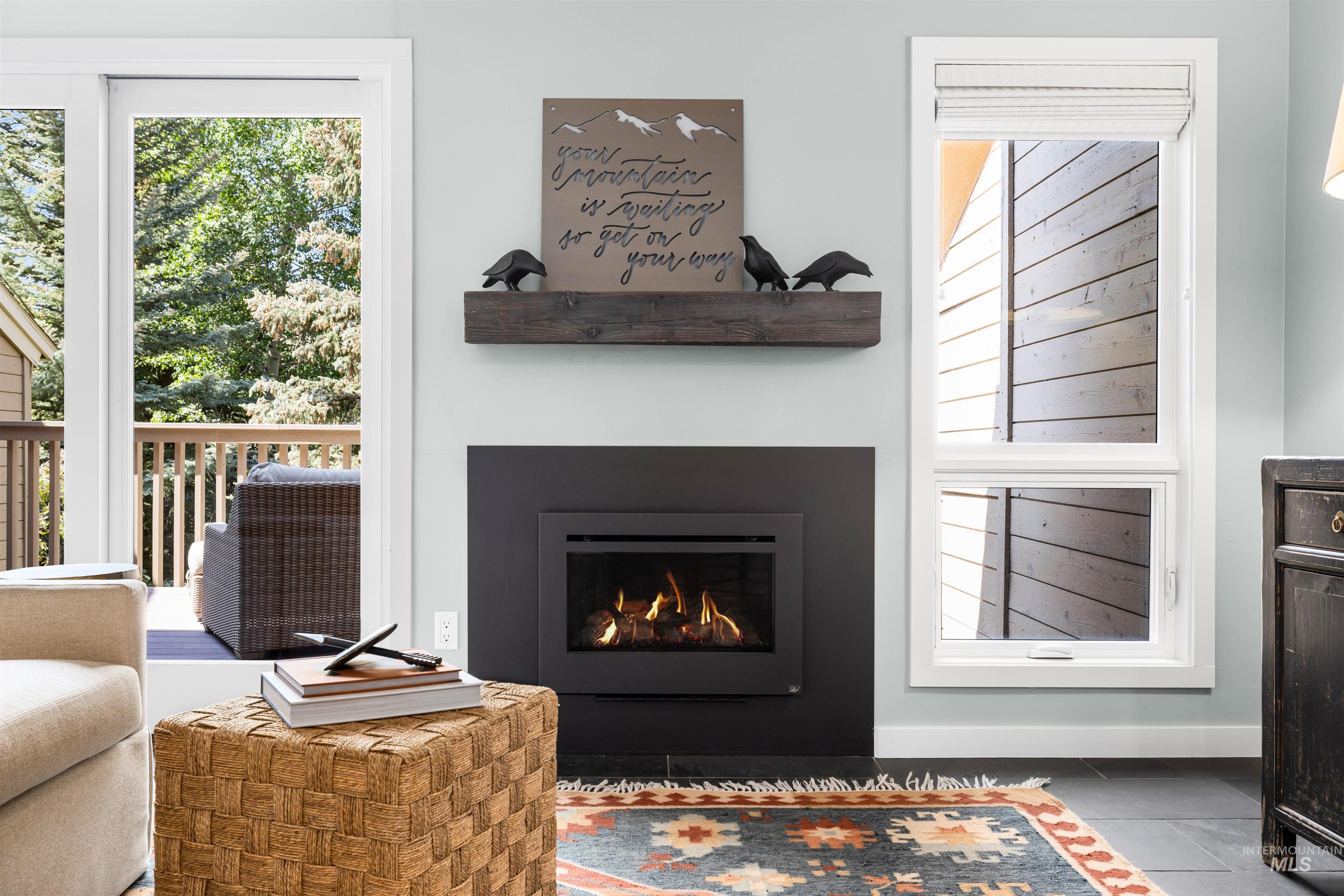 Tiled living area featuring a warm lit fireplace and baseboards