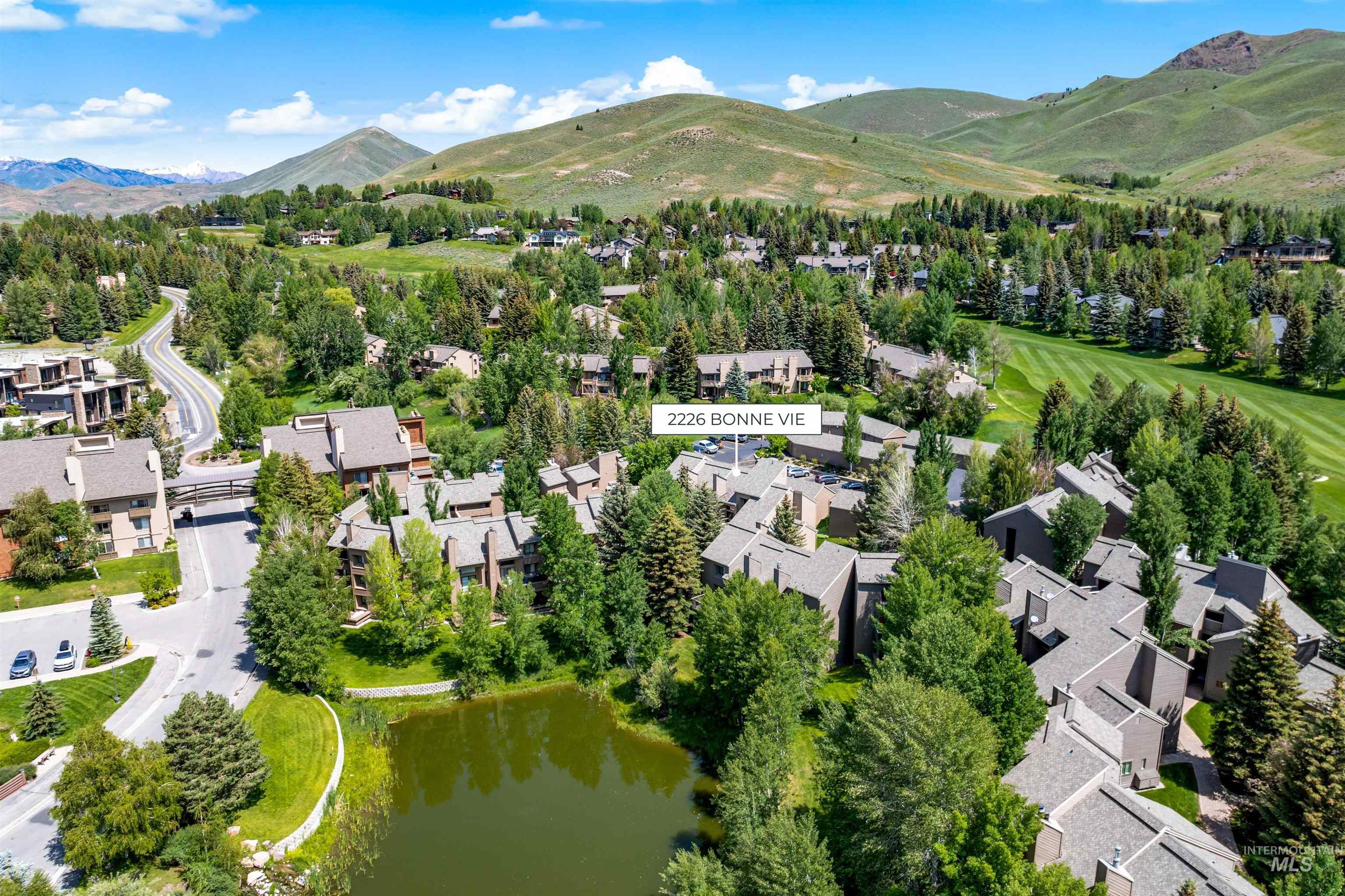 Aerial view of property and surrounding area featuring a water and mountain view and nearby suburban area