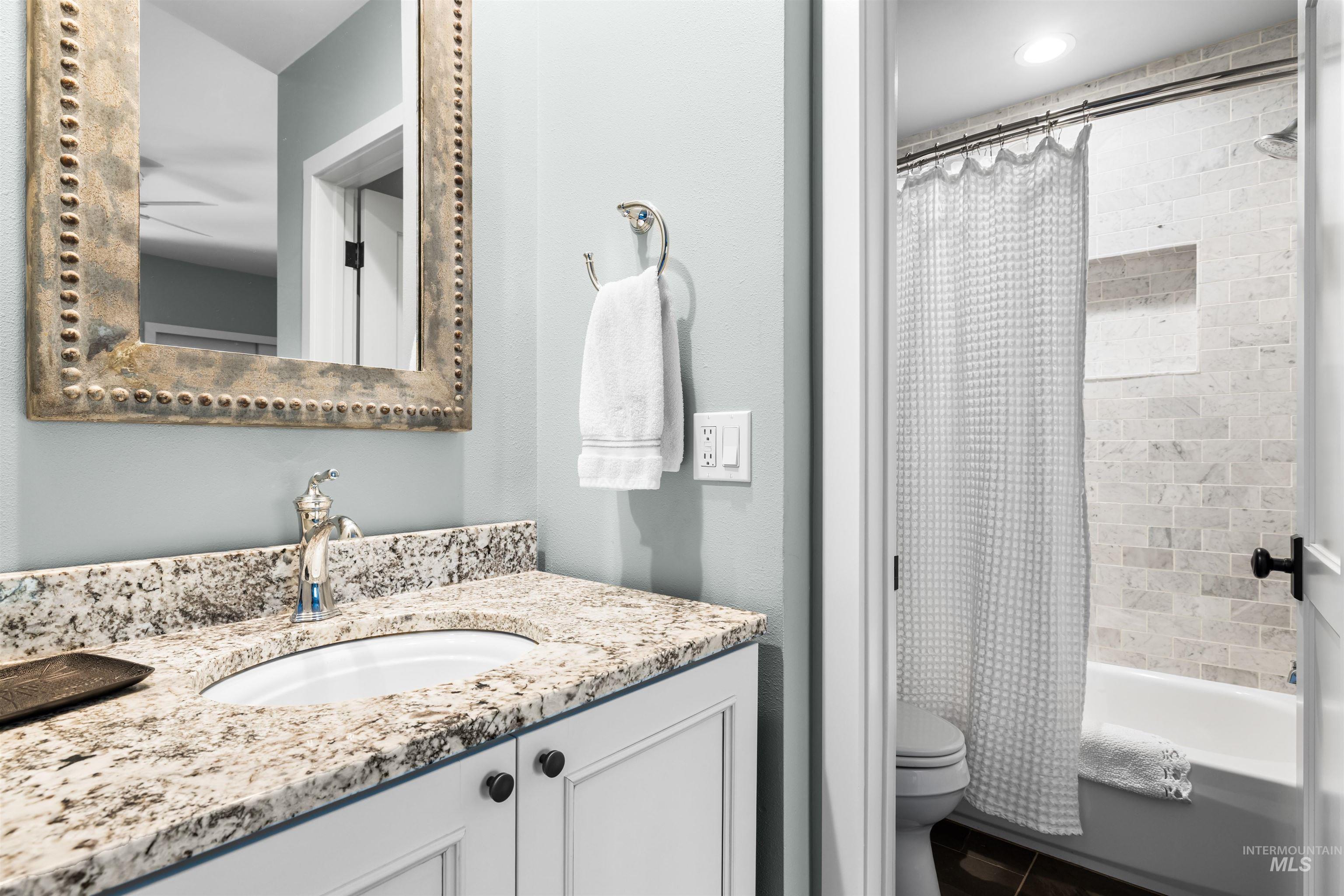 Bathroom featuring vanity, shower / bath combo, and tile patterned flooring
