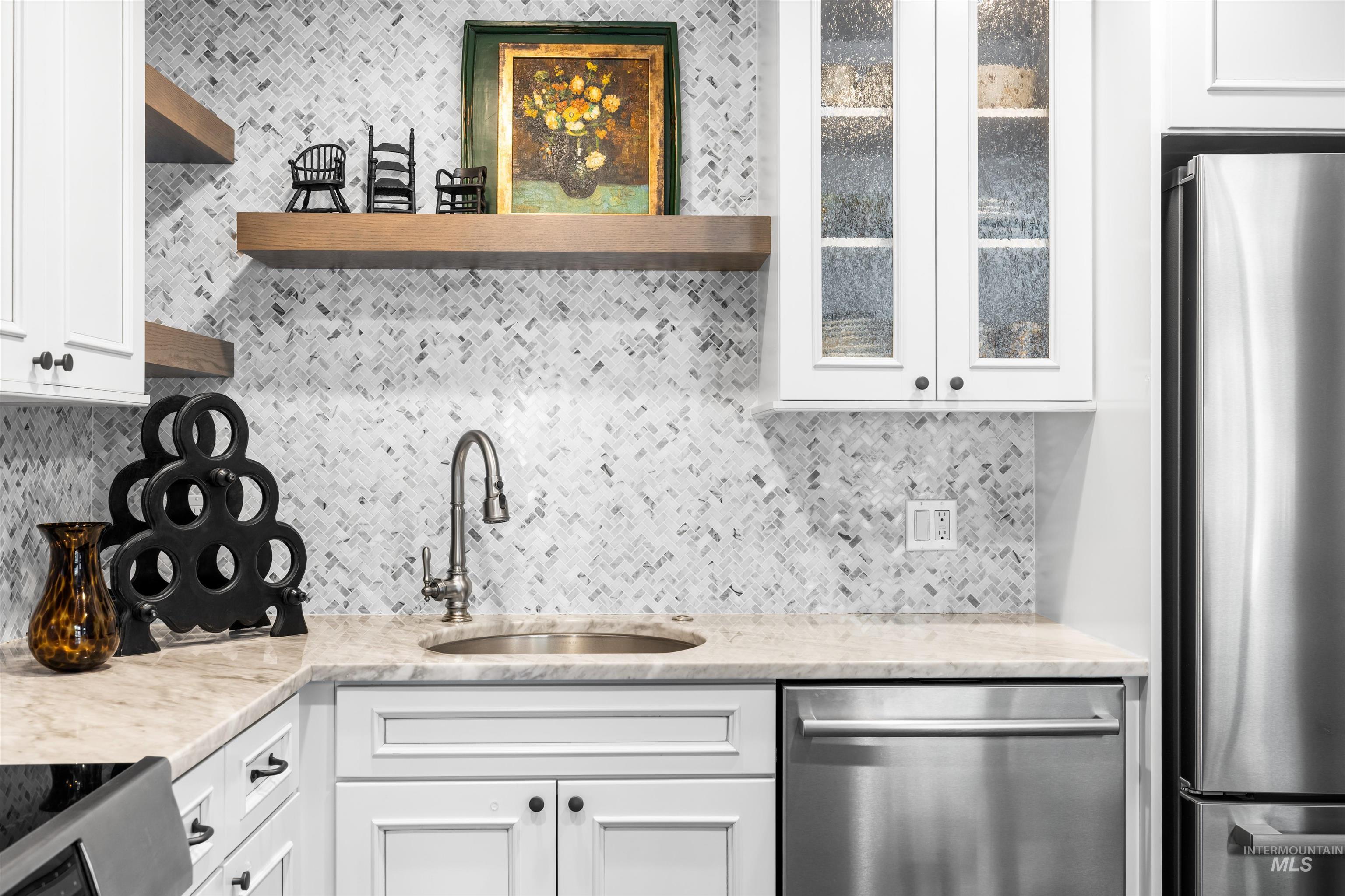 Kitchen with appliances with stainless steel finishes, open shelves, decorative backsplash, and white cabinetry