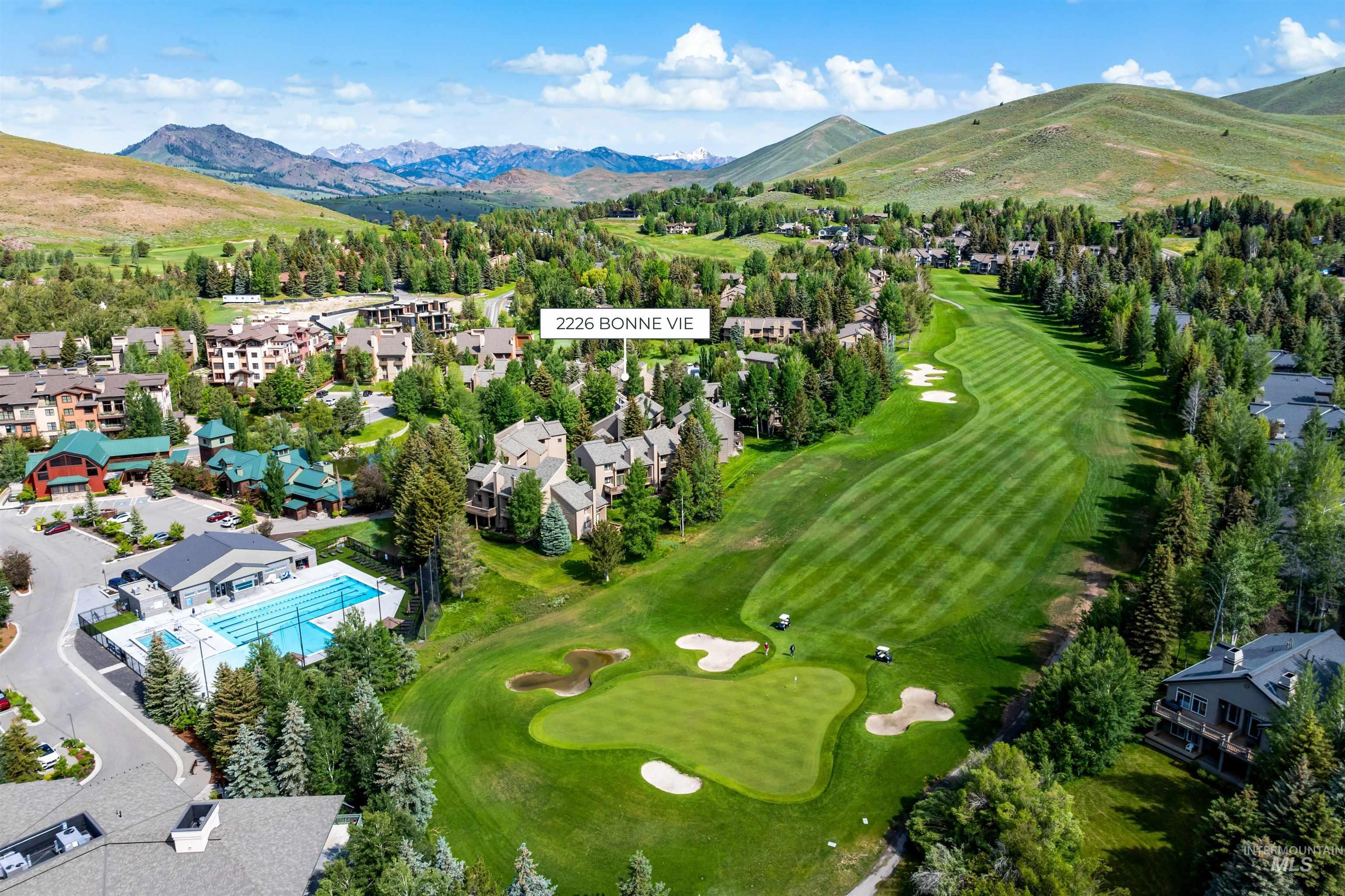 Aerial perspective of suburban area with a mountain backdrop and a golf course