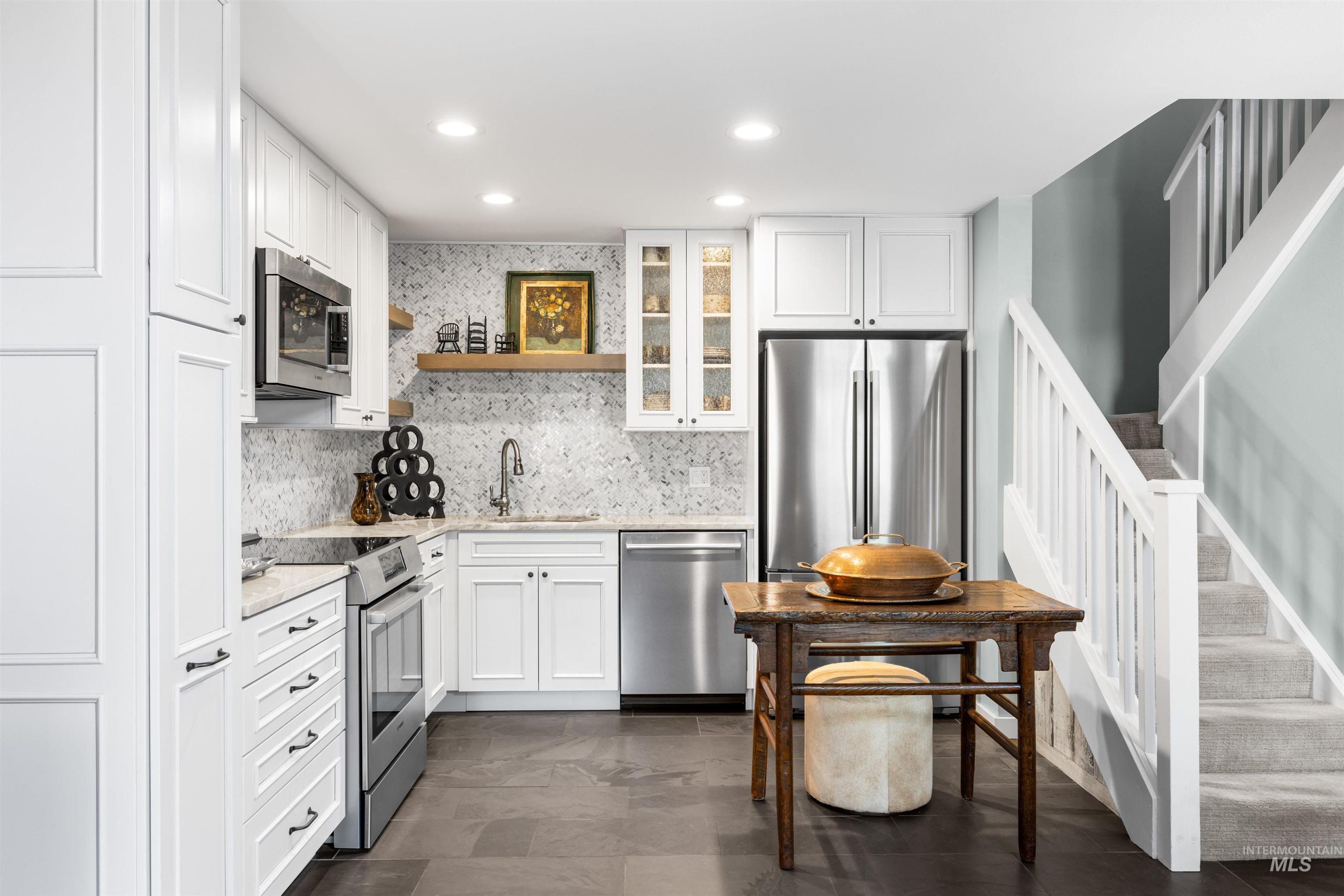Kitchen with appliances with stainless steel finishes, decorative backsplash, white cabinetry, and recessed lighting