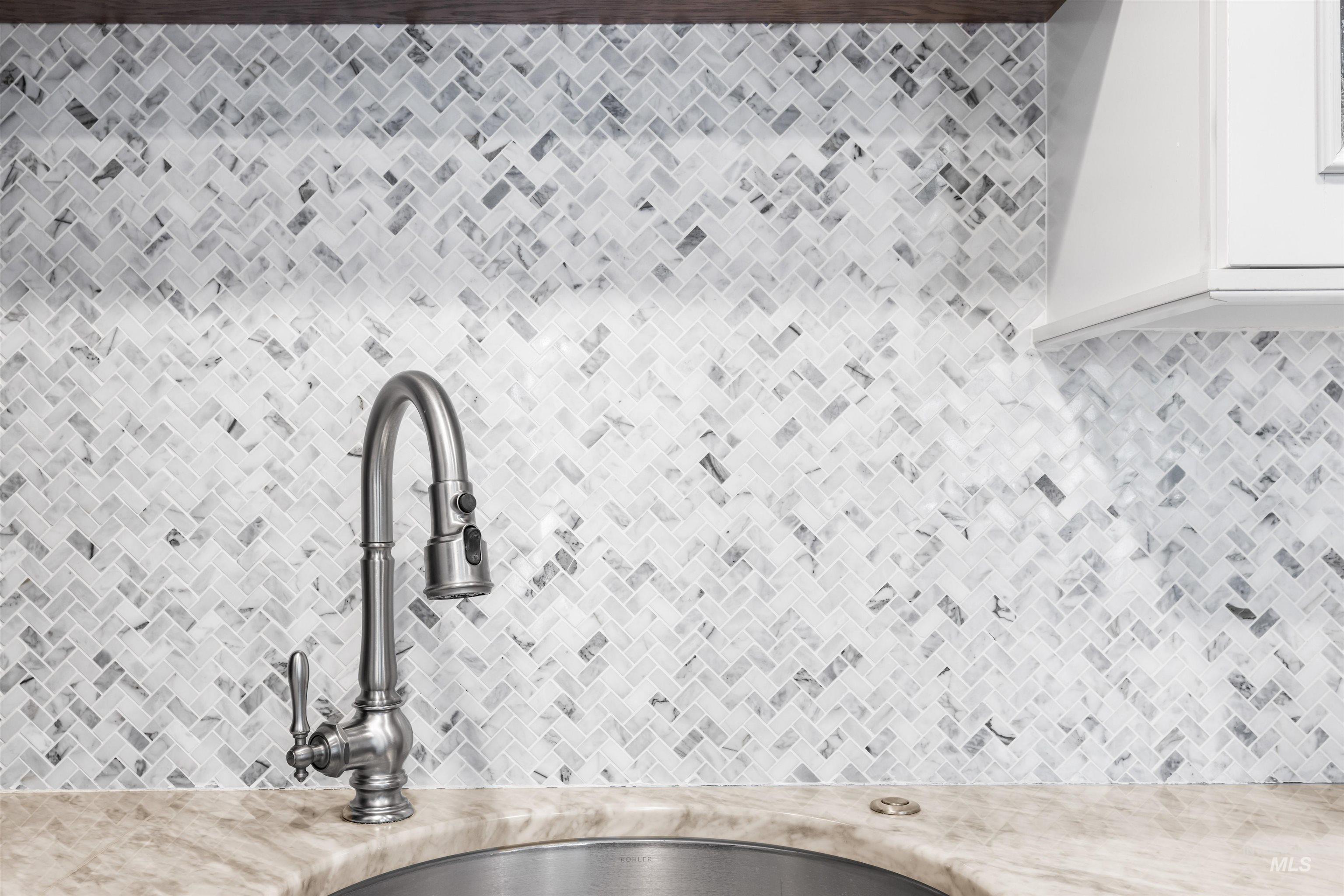 Kitchen view of pot filler, white cabinetry, and decorative backsplash