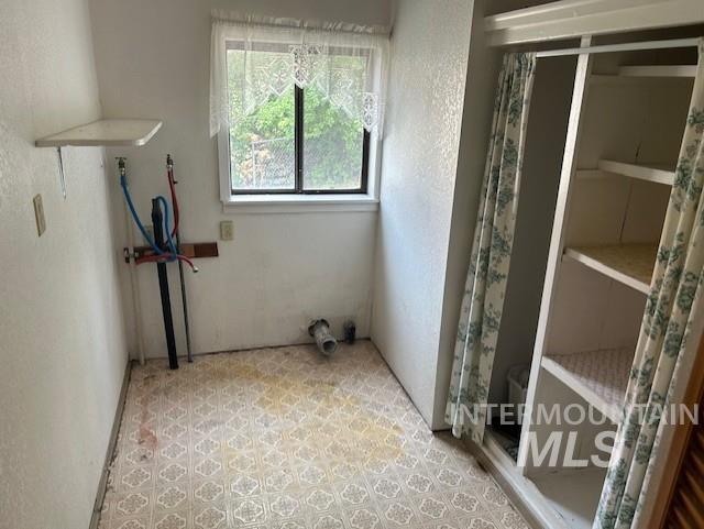 Laundry room with a textured wall and light floors