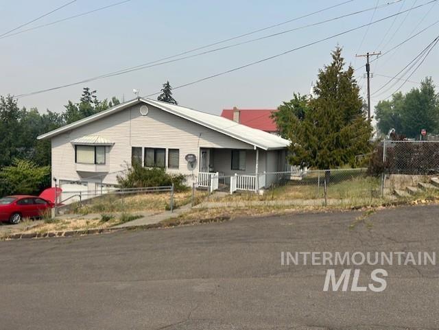 View of front facade featuring a fenced front yard, an attached garage, and a porch