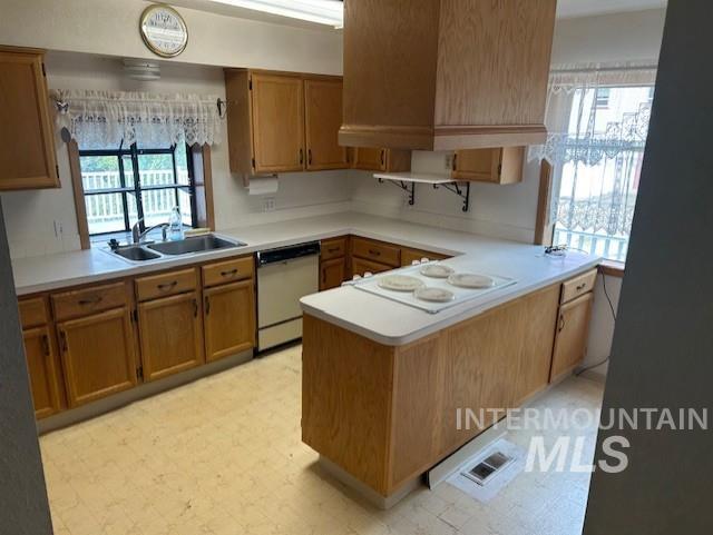 Kitchen featuring light floors, a peninsula, light countertops, and plenty of natural light