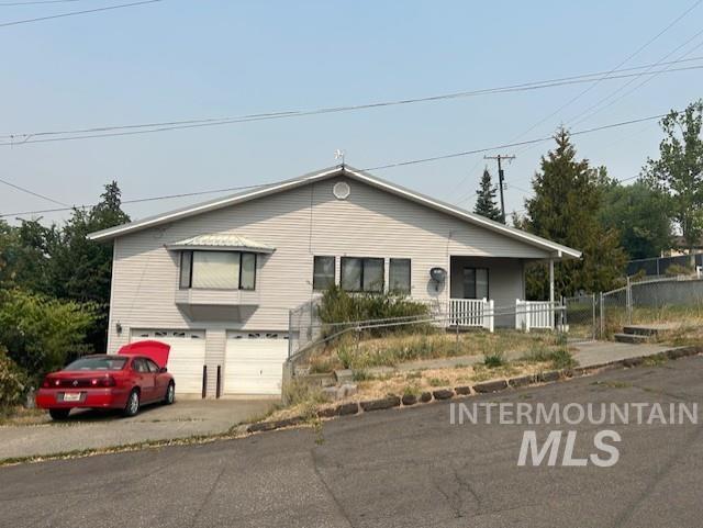 View of front of home with an attached garage, driveway, and covered porch
