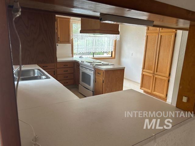 Kitchen featuring a peninsula, light countertops, and range
