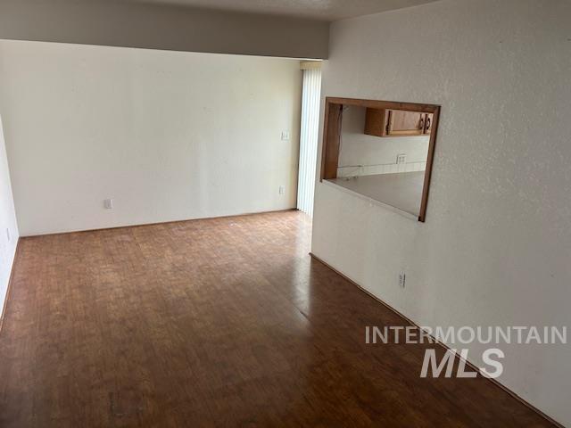Unfurnished living room featuring dark wood-style floors