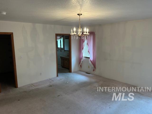 Unfurnished dining area with a chandelier, carpet floors, and a textured ceiling