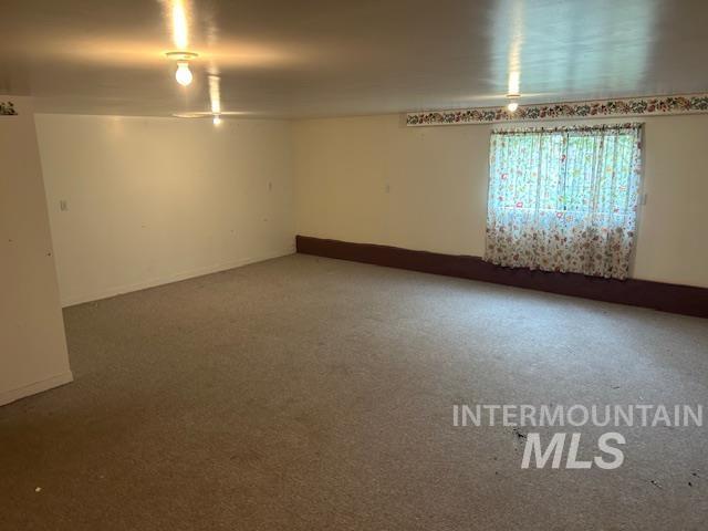 Spare room featuring baseboards and carpet floors