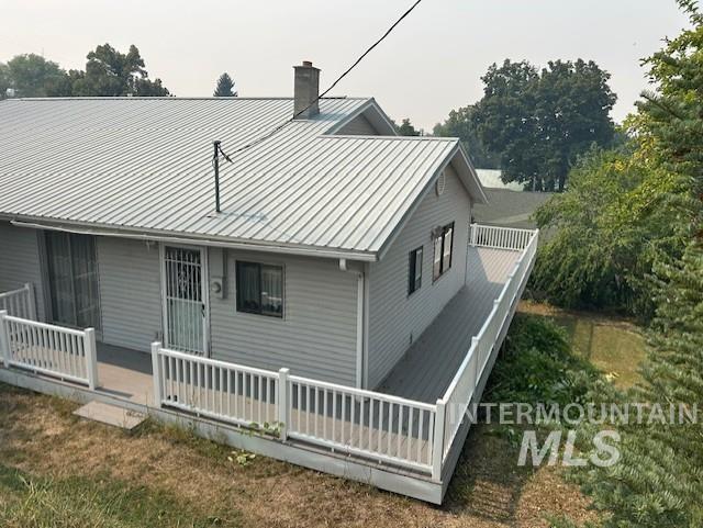 Rear view of property with a deck, a chimney, and a metal roof