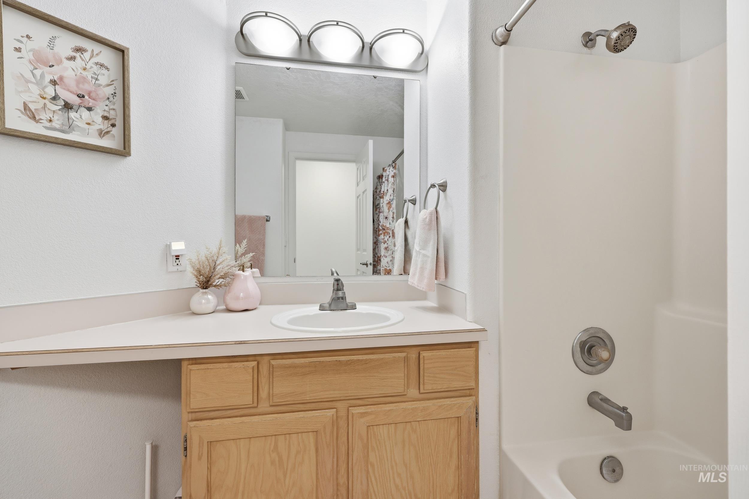 Full bathroom featuring vanity, shower / tub combo, and a textured wall