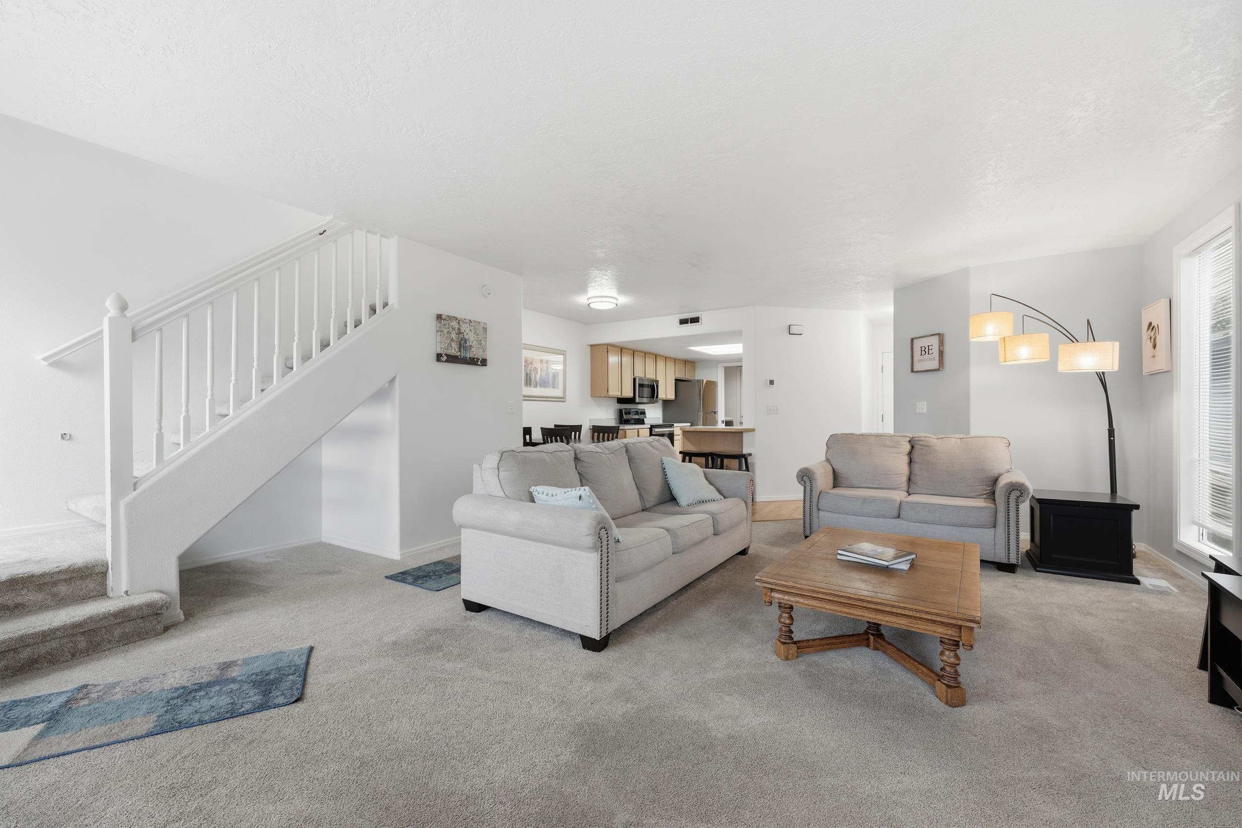 Living area with light colored carpet and stairs