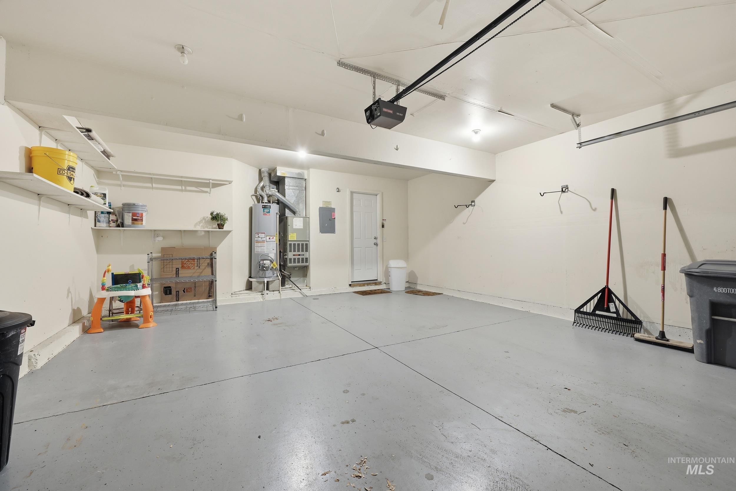 Garage with water heater, electric panel, a garage door opener, and heating unit