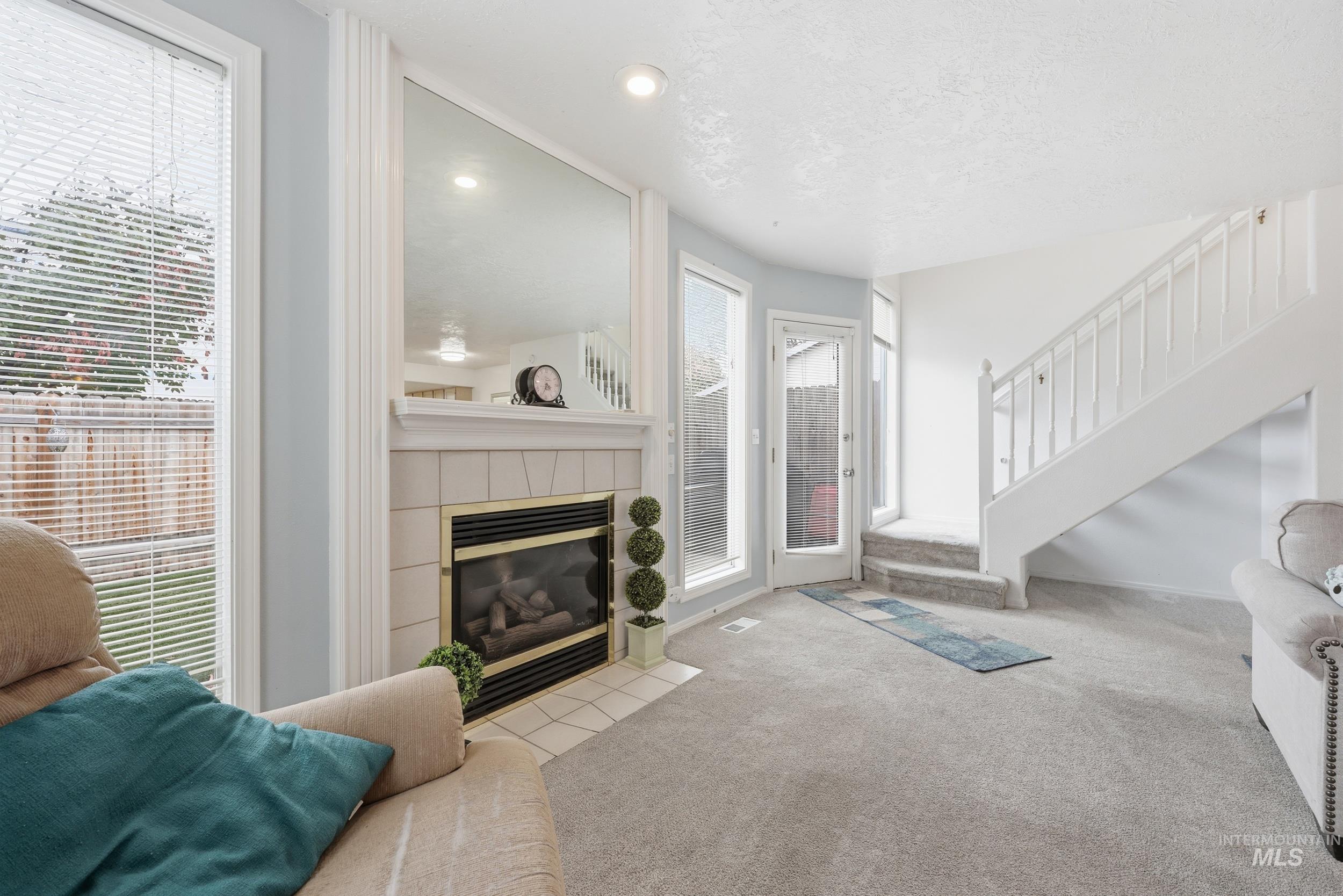 Living area with stairs, a fireplace, carpet flooring, and recessed lighting