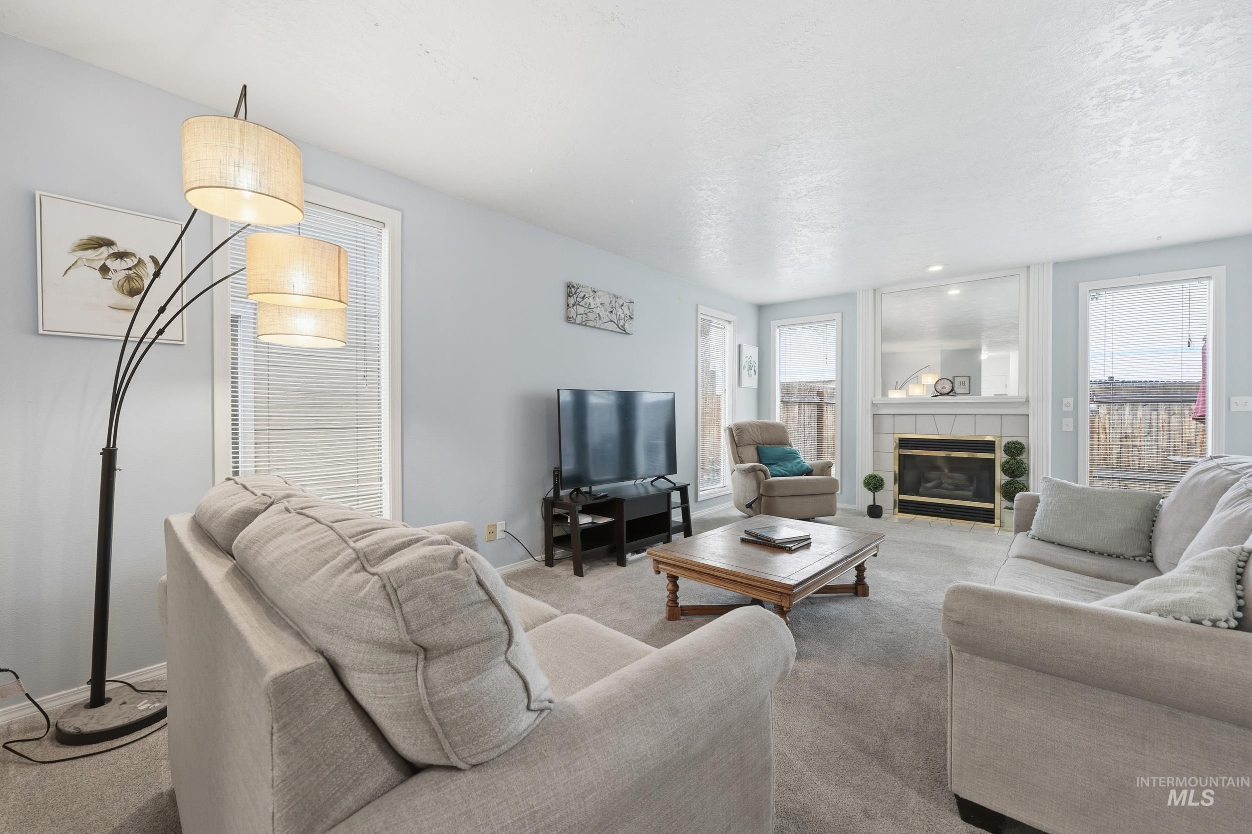 Carpeted living room with a tiled fireplace and baseboards