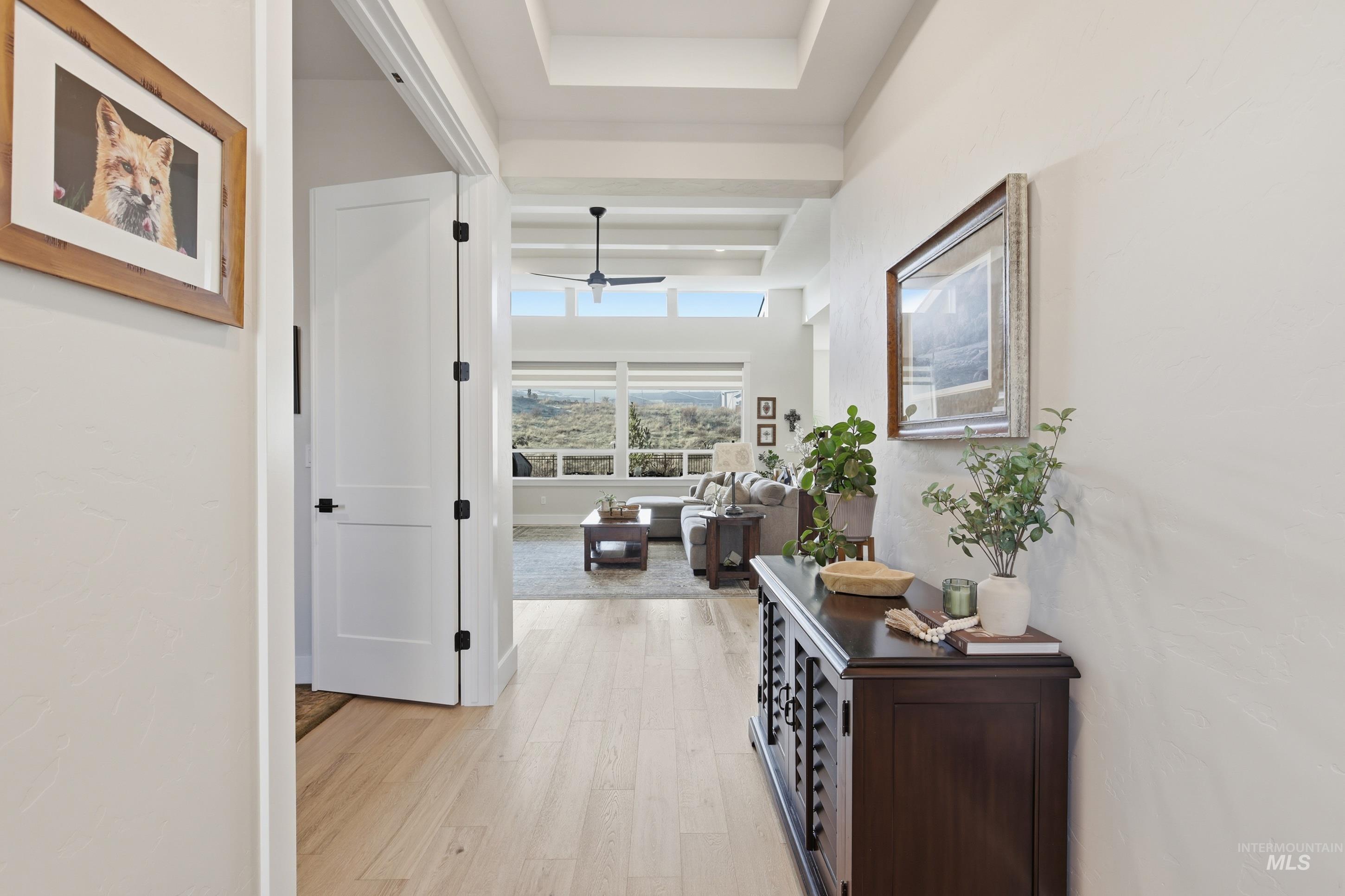 Hallway featuring light wood-style floors and a tray ceiling