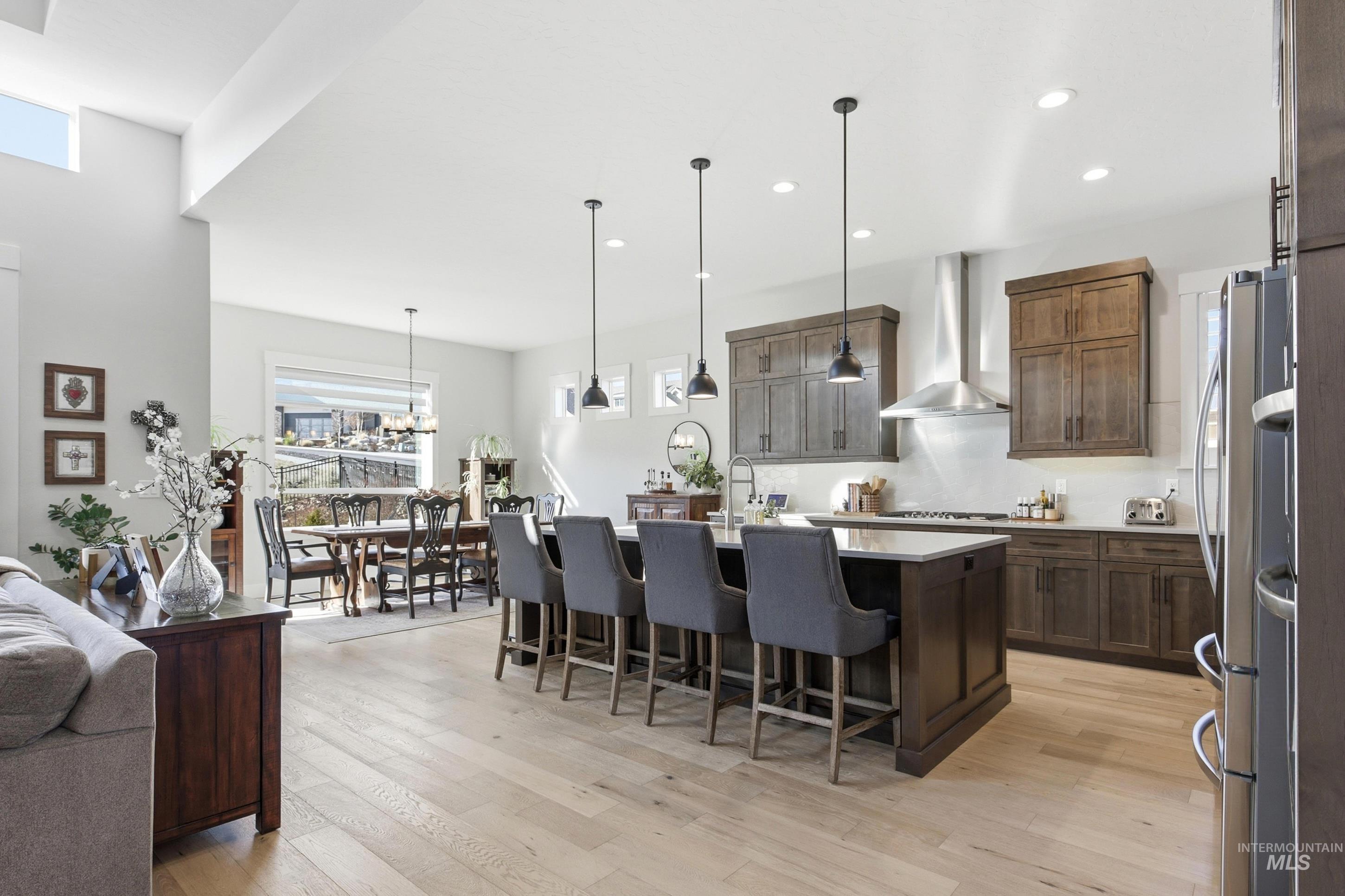 Kitchen with a breakfast bar area, decorative light fixtures, a kitchen island with sink, light wood-style flooring, and recessed lighting