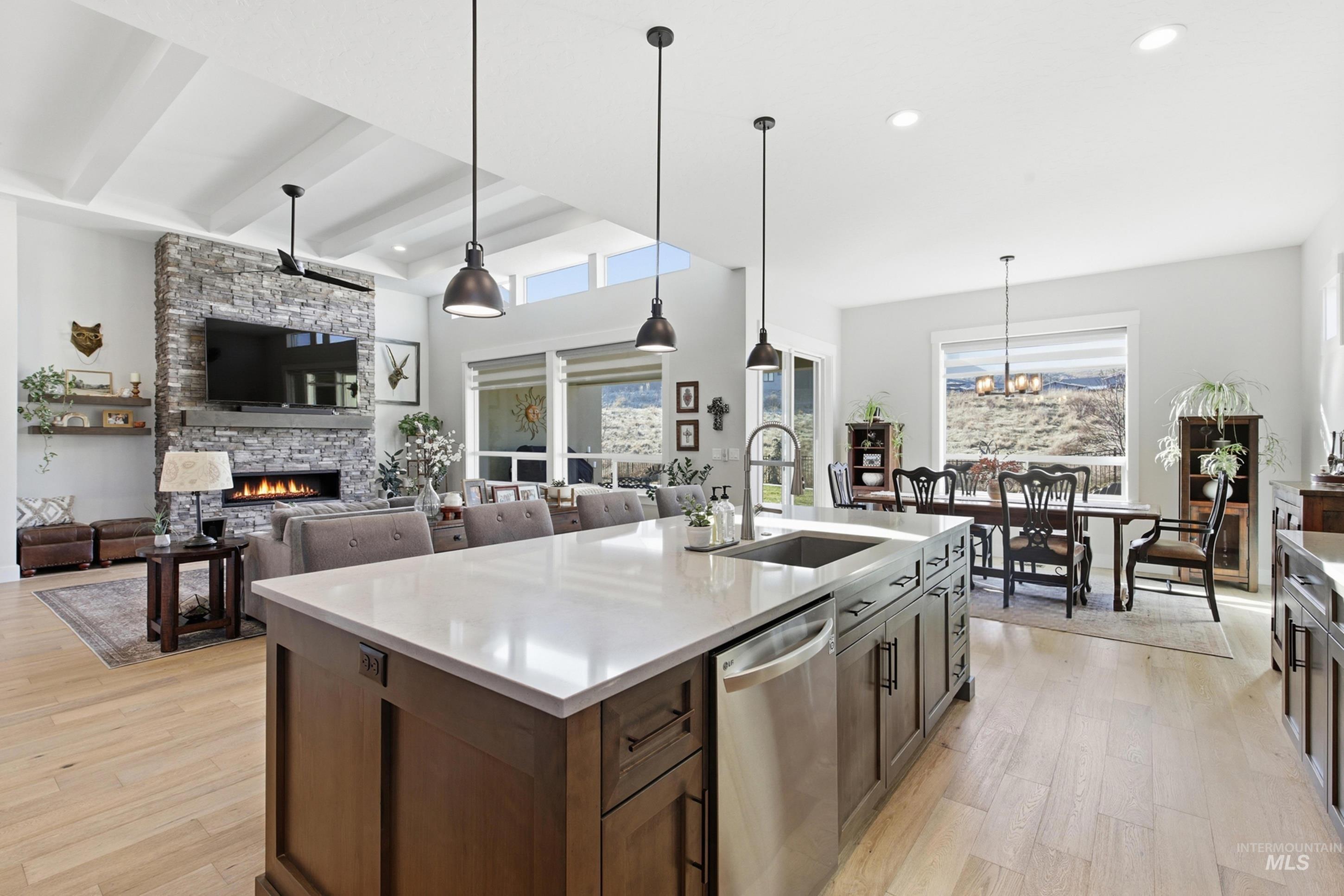 Kitchen featuring hanging light fixtures, a fireplace, light wood-type flooring, stainless steel dishwasher, and recessed lighting