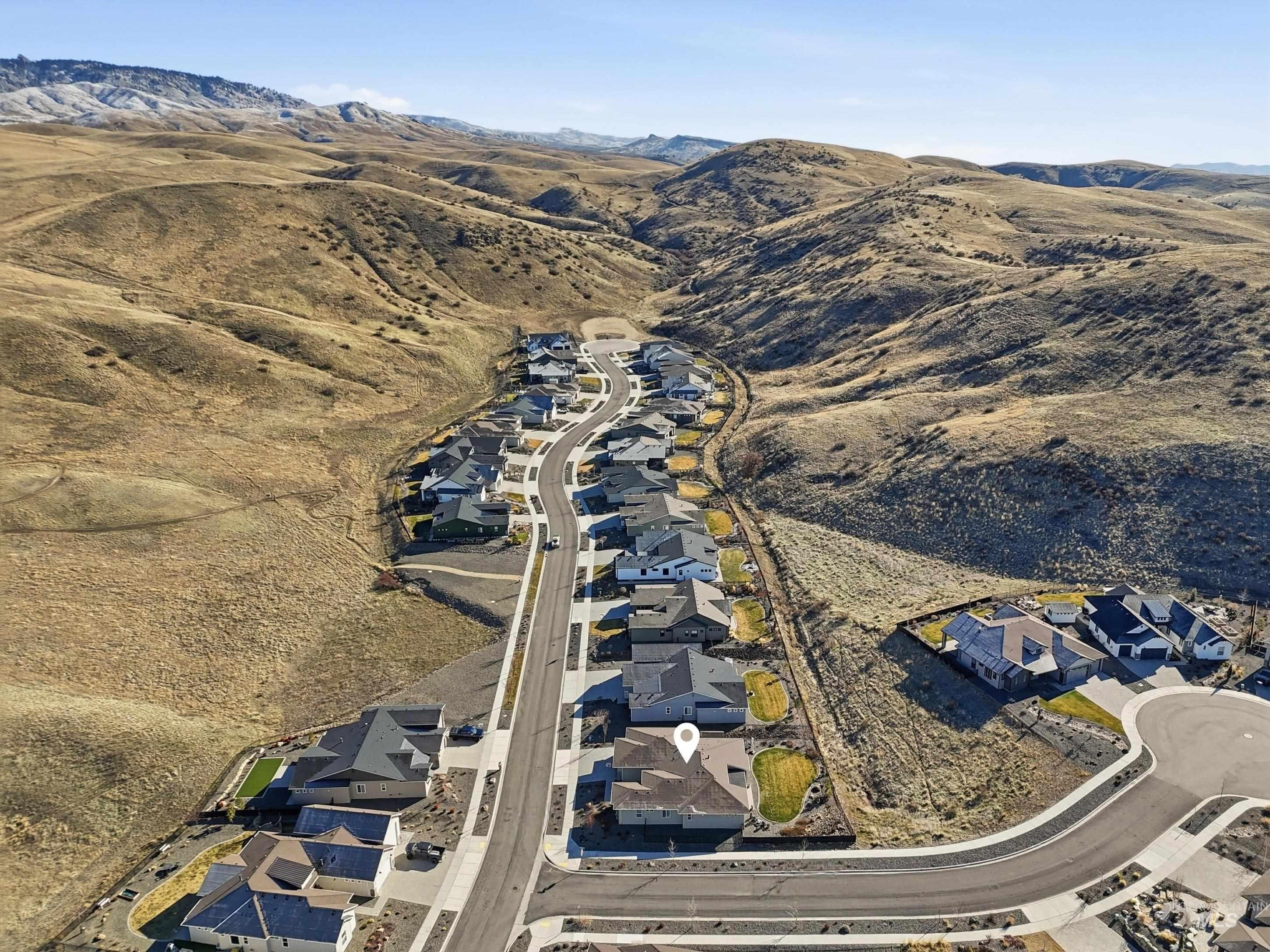 Aerial overview of property's location with a mountain backdrop and nearby suburban area