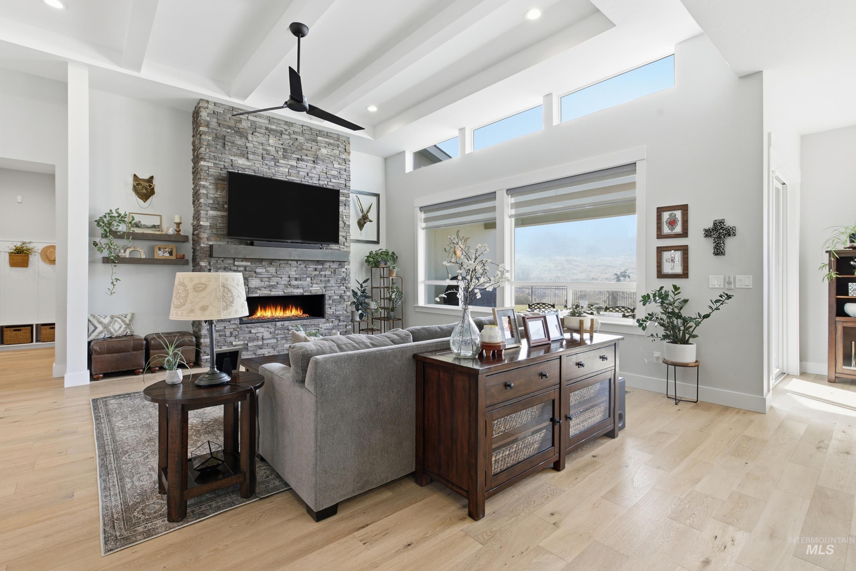 Living room with a fireplace, light wood-type flooring, recessed lighting, a ceiling fan, and a towering ceiling