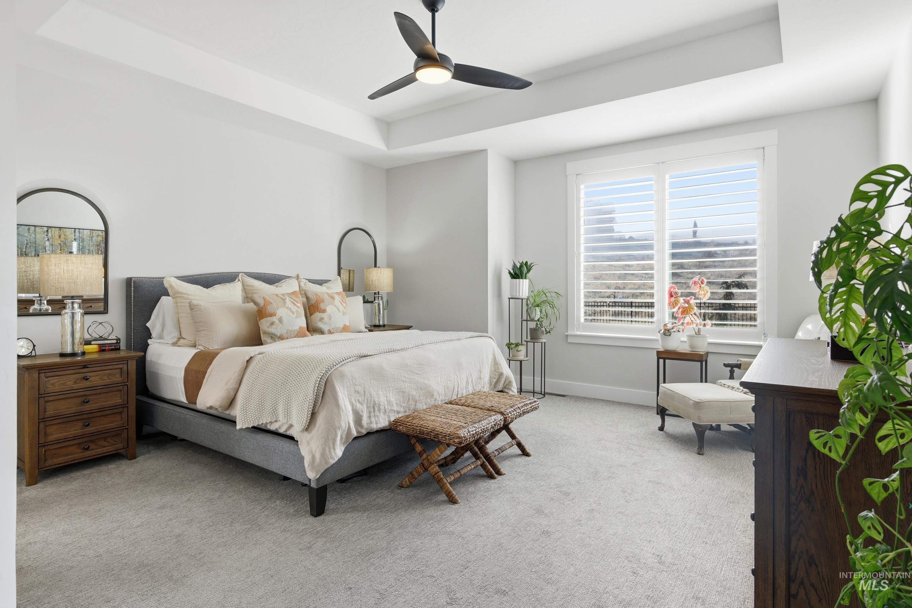 Bedroom featuring a tray ceiling, carpet, and ceiling fan