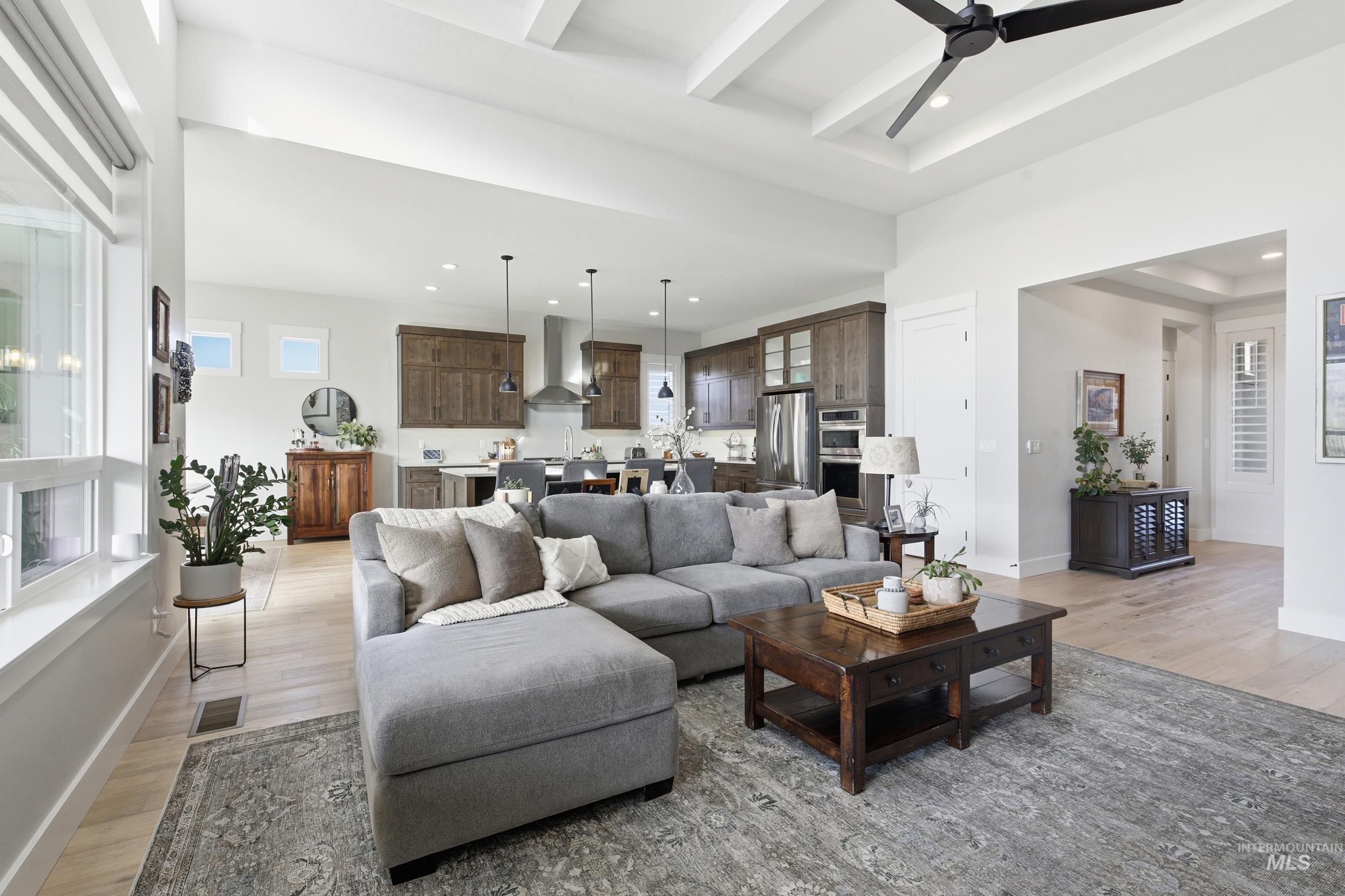 Living room featuring light wood-type flooring, beamed ceiling, ceiling fan, and recessed lighting