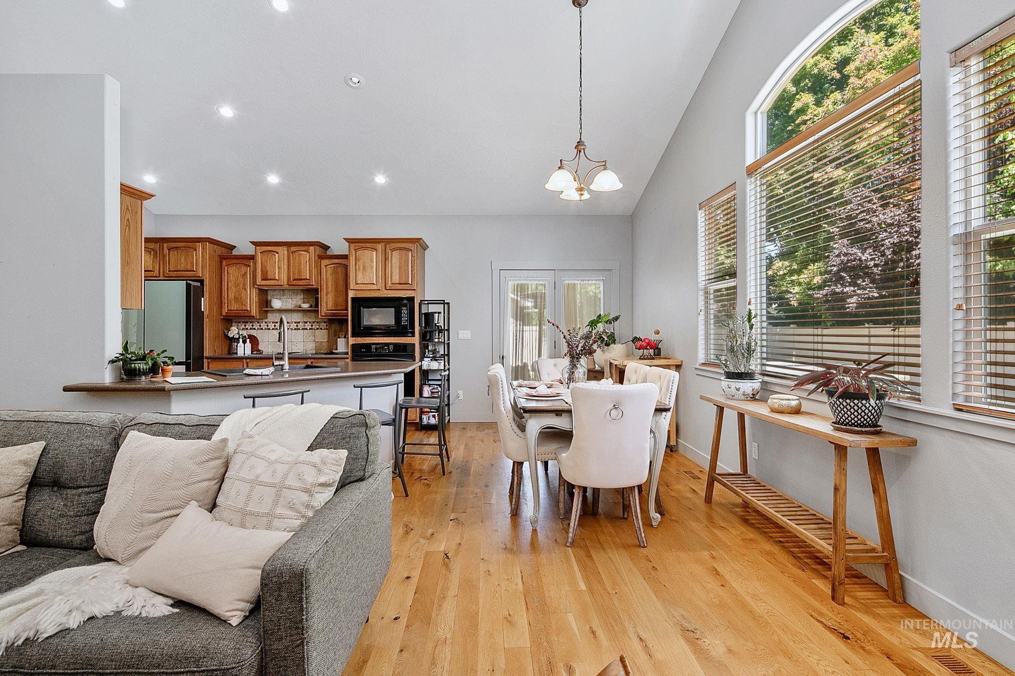 Open-concept living space featuring wood-finish flooring, recessed lighting, and high vaulted ceilings