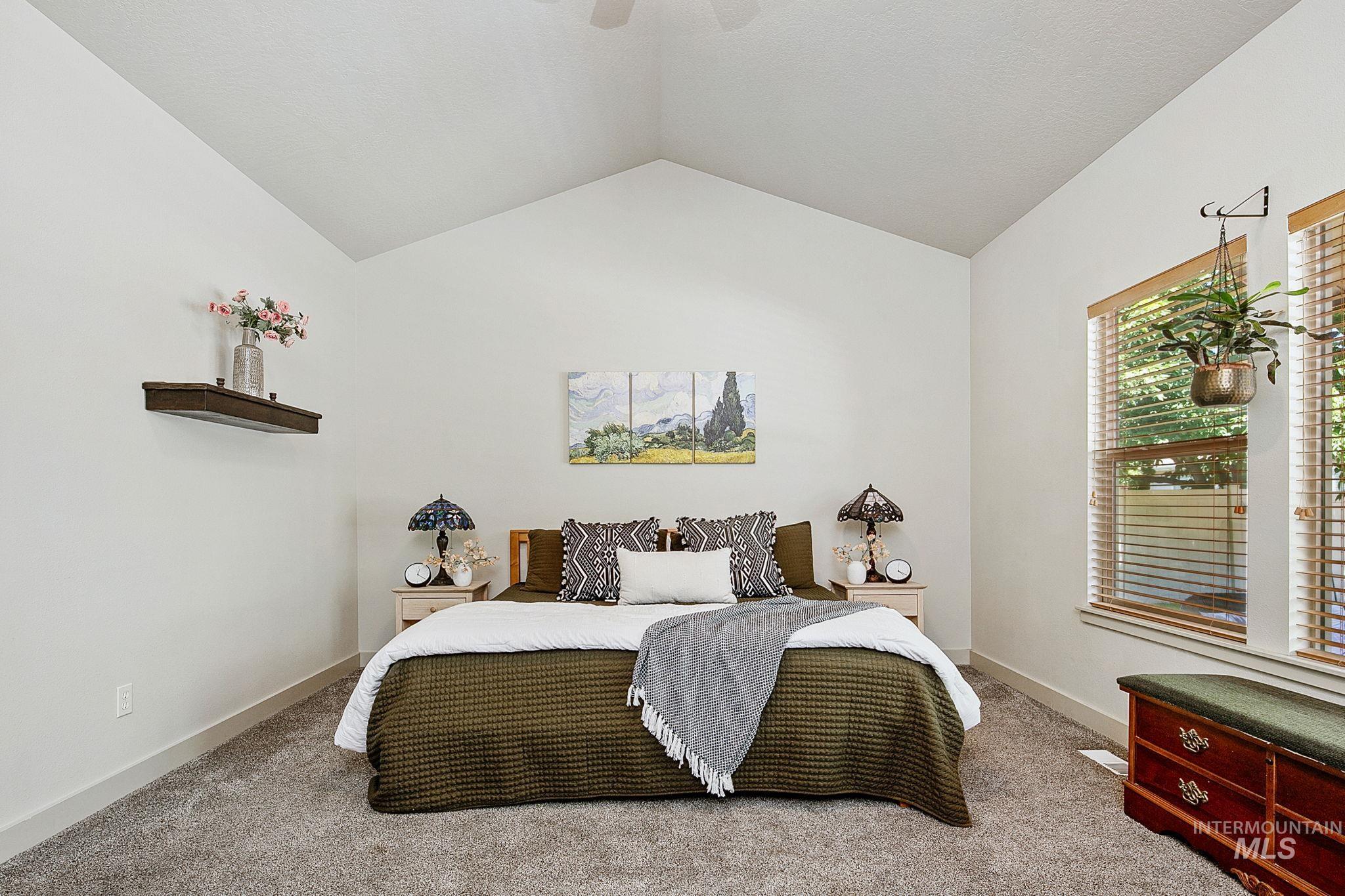 Room with vaulted ceiling, carpeted flooring, and two windows featuring wood blinds
