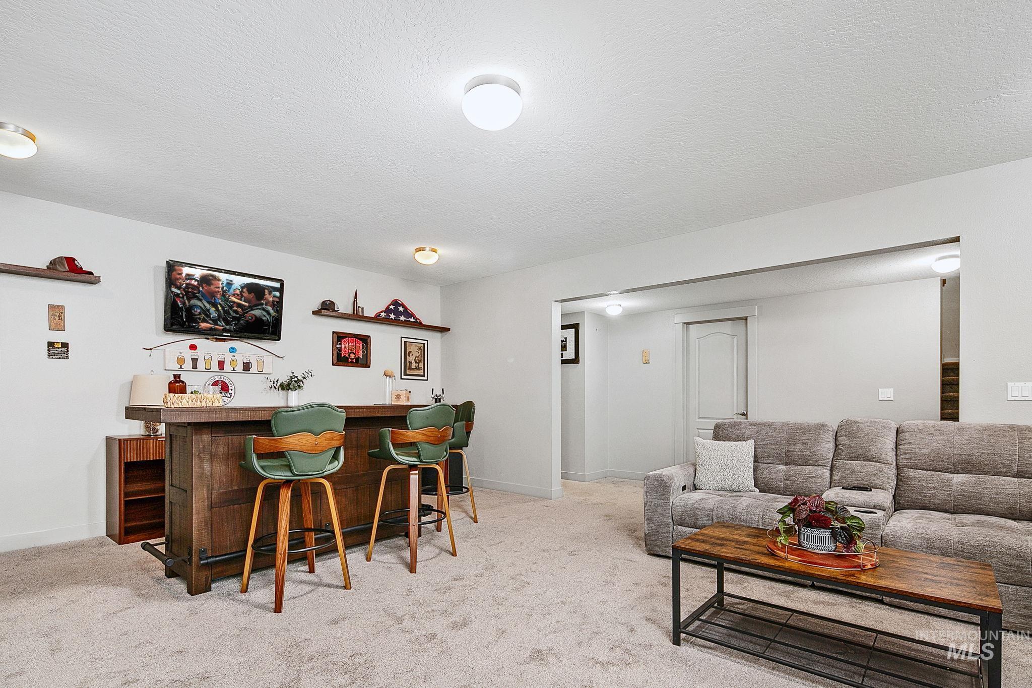 Entertainment area featuring a built-in wood-finish bar with shelving, mounted television, and recessed ceiling lighting