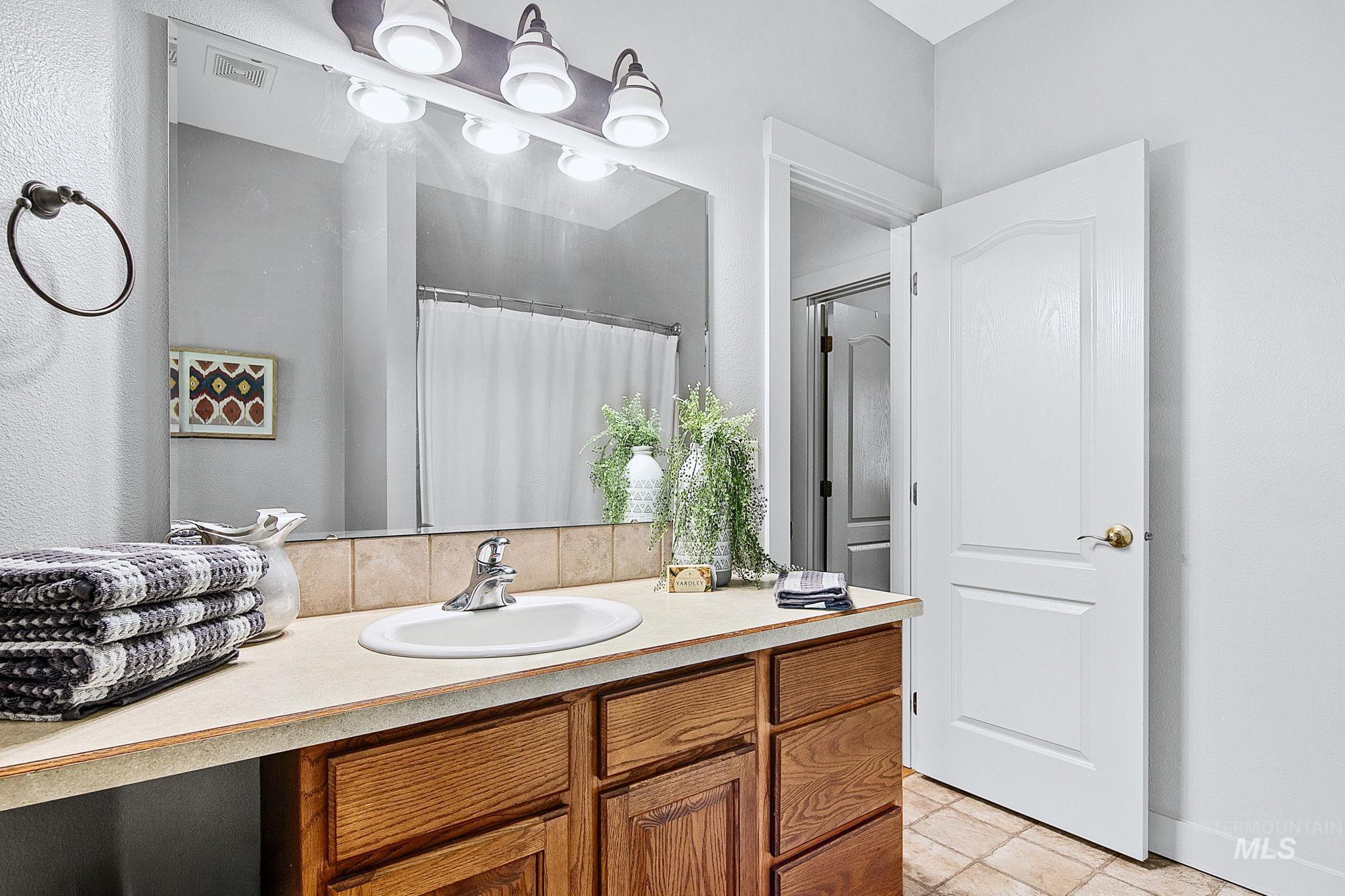 Bathroom vanity featuring wood-finish cabinetry, a rectangular undermount sink, and a countertop with tile backsplash