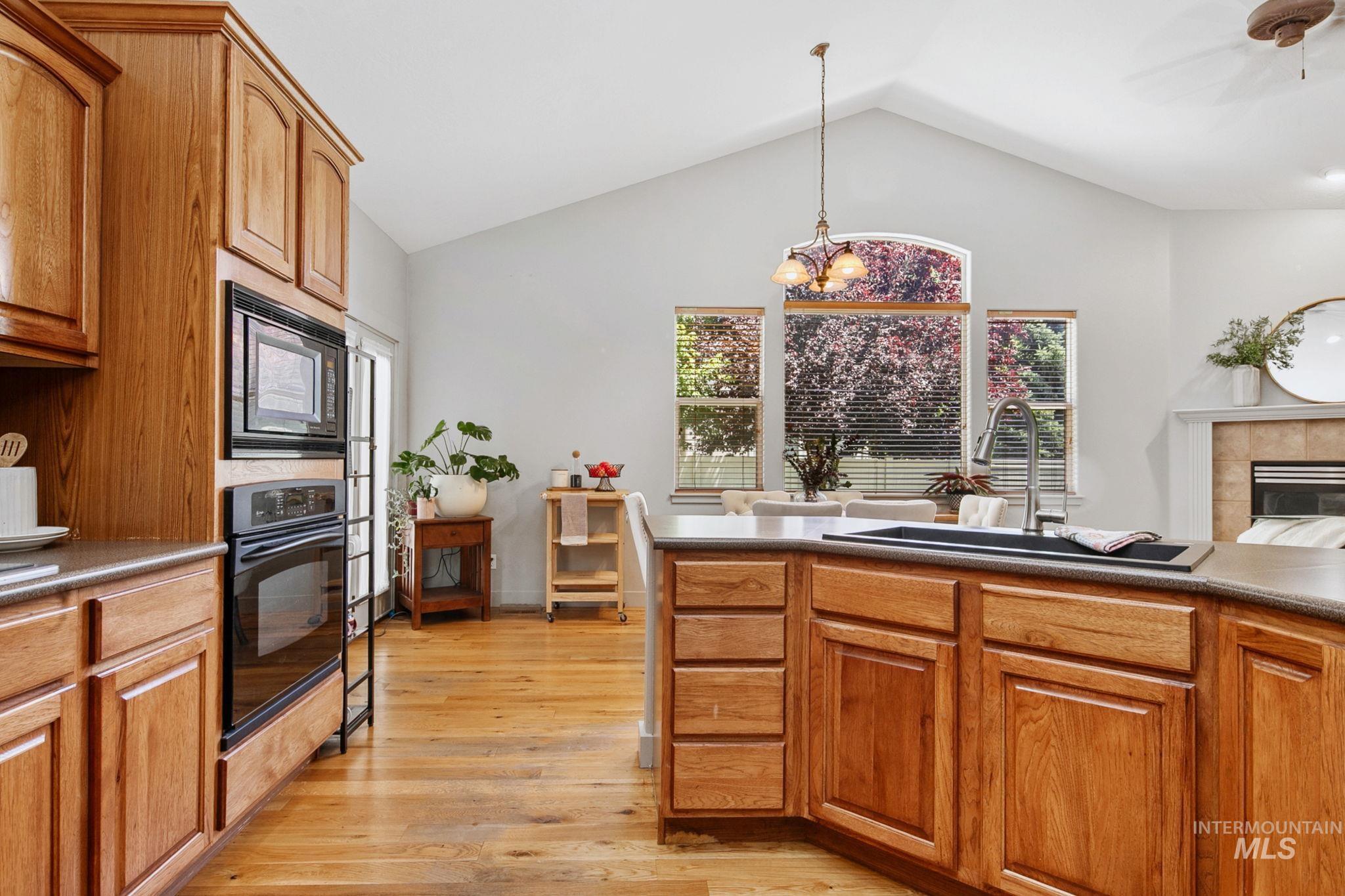 Kitchen featuring wood-finish cabinetry, built-in black appliances, and durable countertops