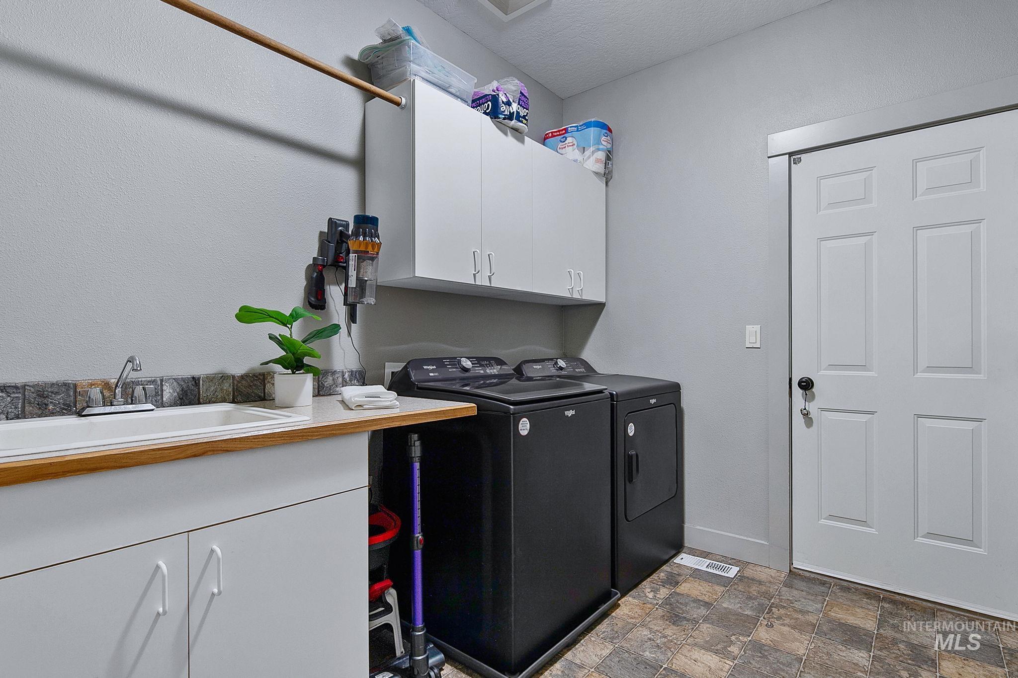Laundry area featuring a built-in utility sink, wood-finish countertop, and white cabinetry