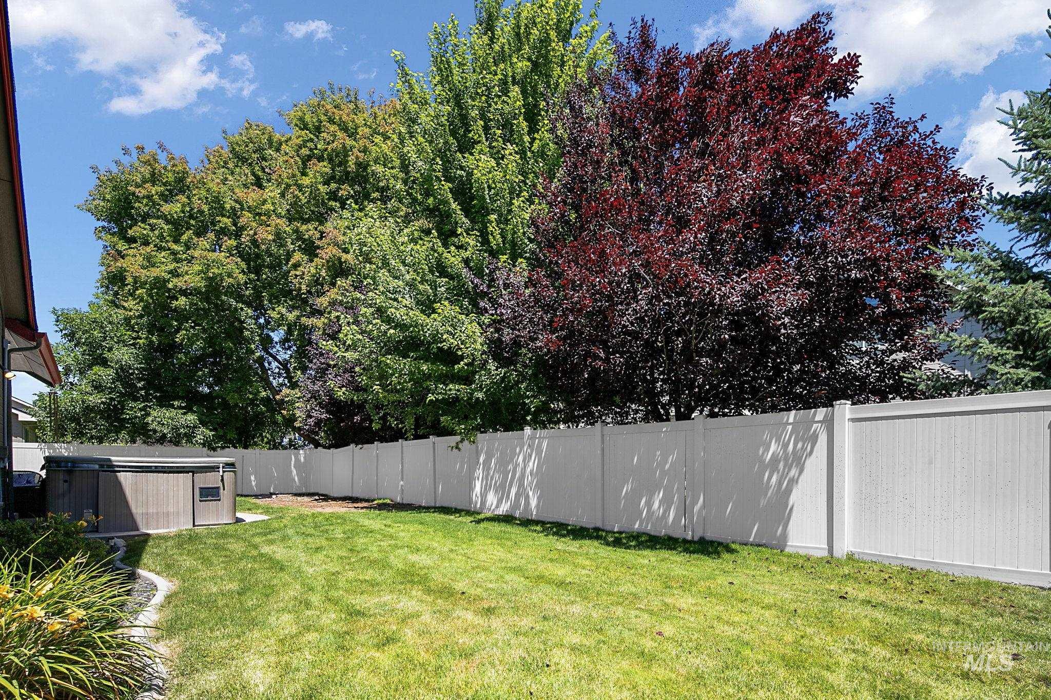 Expansive green lawn with a white privacy fence