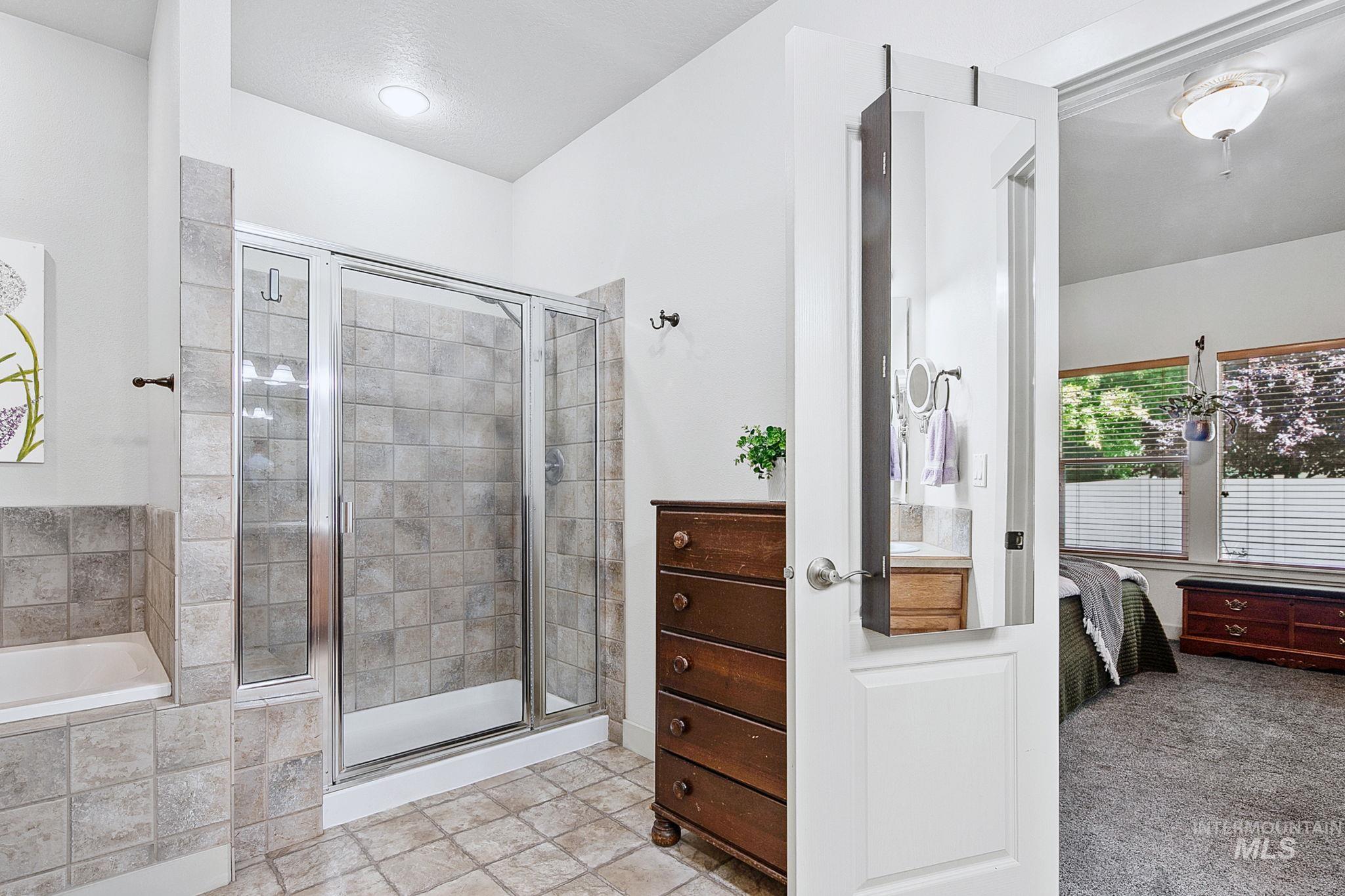 Tiled shower with glass enclosure, complementing a built-in tub with tile surround