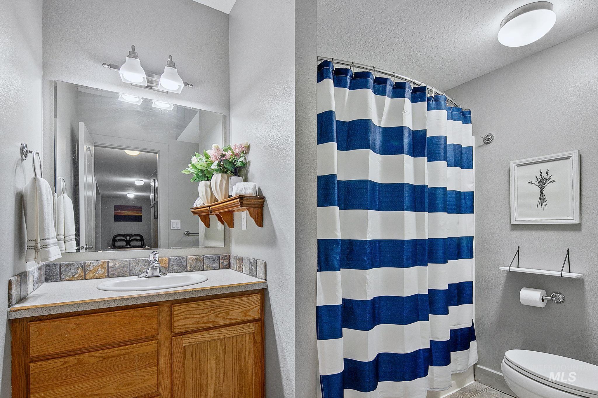 Bathroom featuring a vanity with wood-finish cabinetry, a drop-in sink, and a tiled backsplash