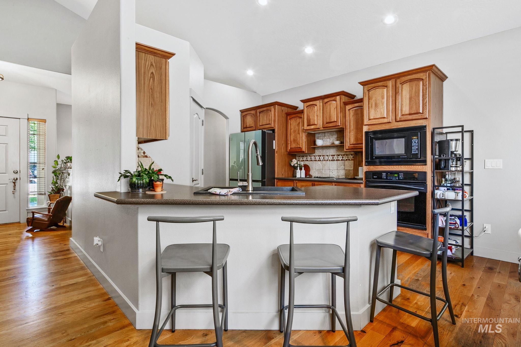 Kitchen featuring a peninsula island with counter seating, wood-finish cabinetry, a tile backsplash, and recessed lighting
