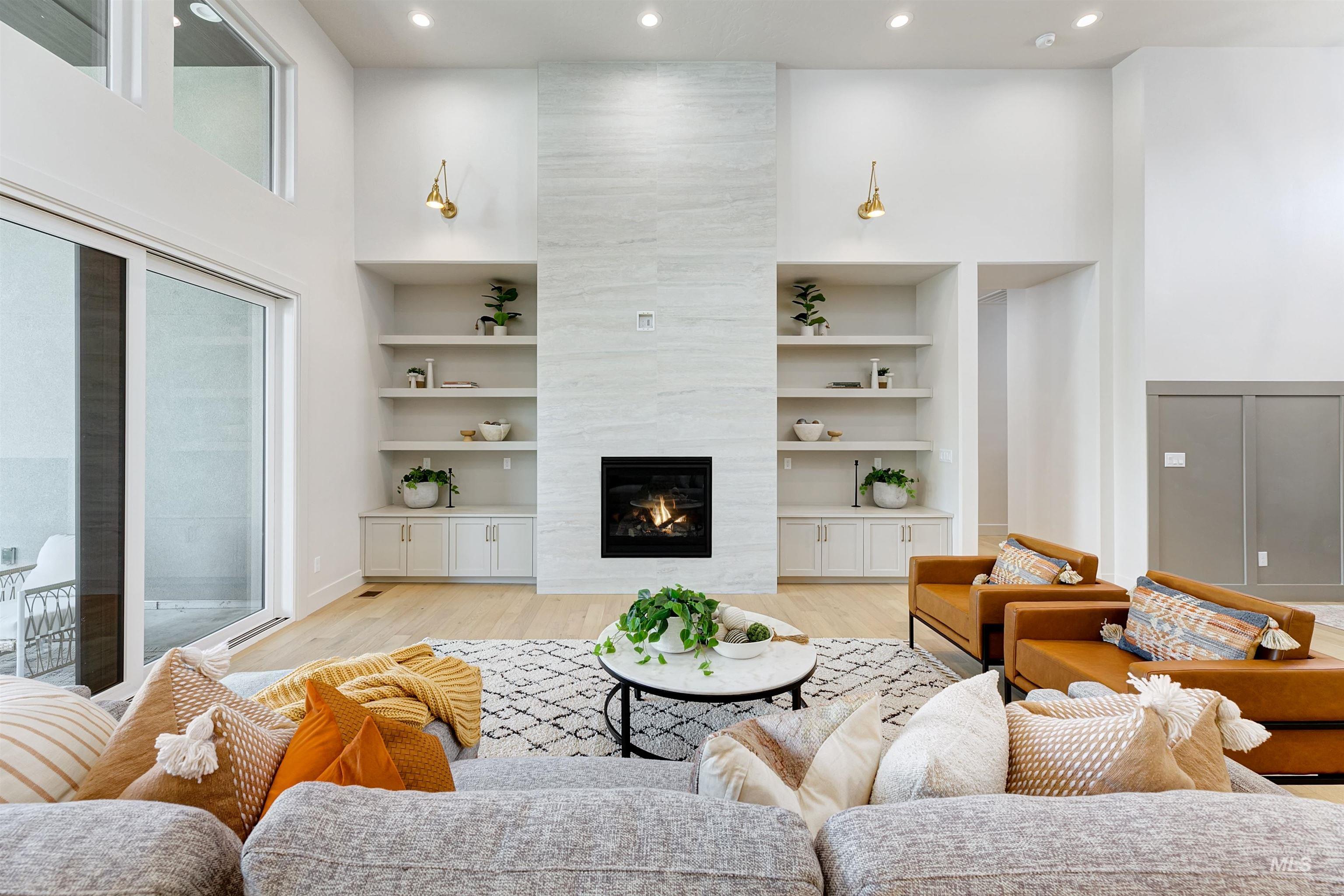 Living area featuring a high ceiling, a premium fireplace, light wood-type flooring, and recessed lighting